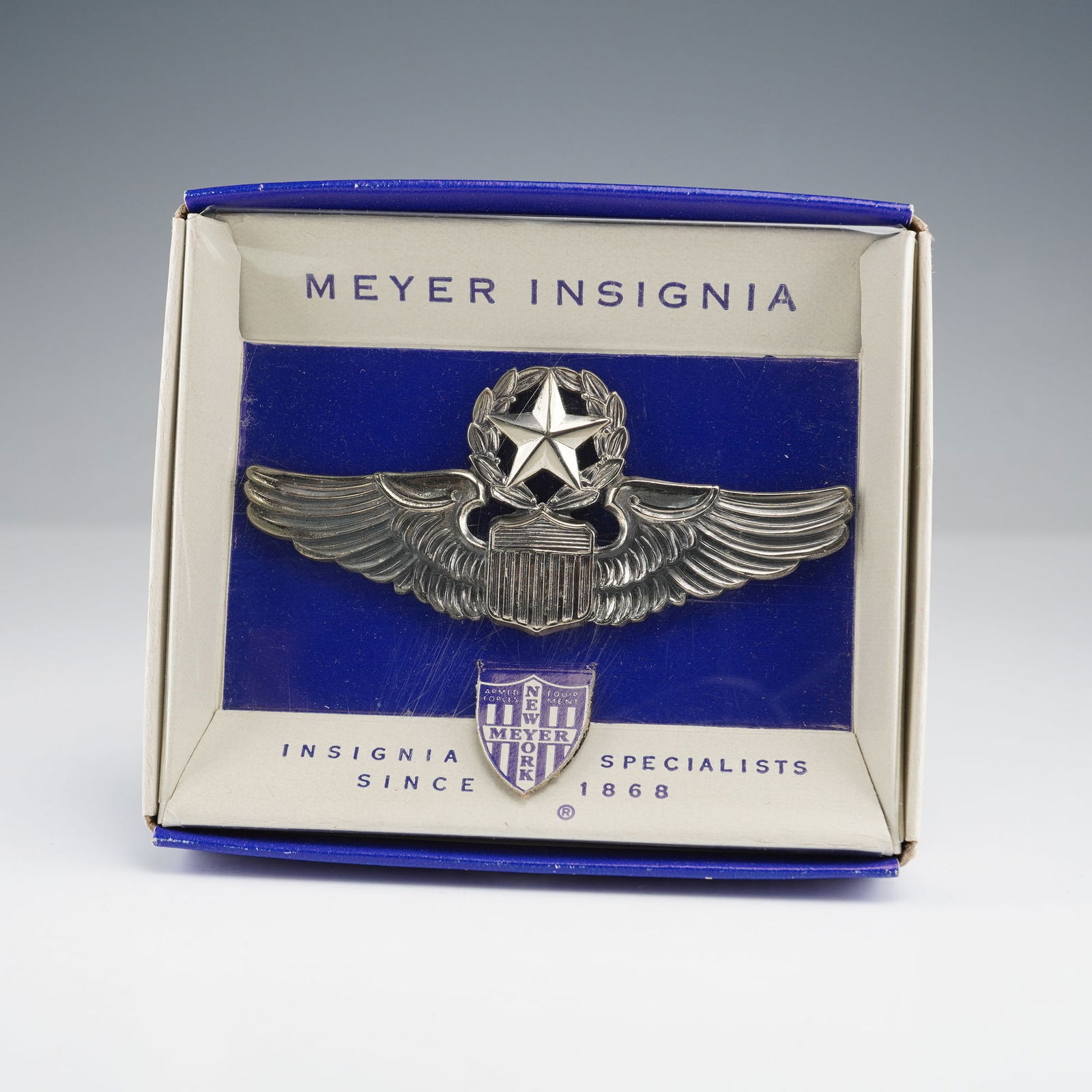 N.S. Meyer U.S. Air Force Command Pilot Wing Insignia in Original Box: An N.S. Meyer U.S. Air Force Command Pilot Wing insignia. This silver-toned metal military-style badge features a central five-pointed star within a laurel wreath, positioned above a shield and