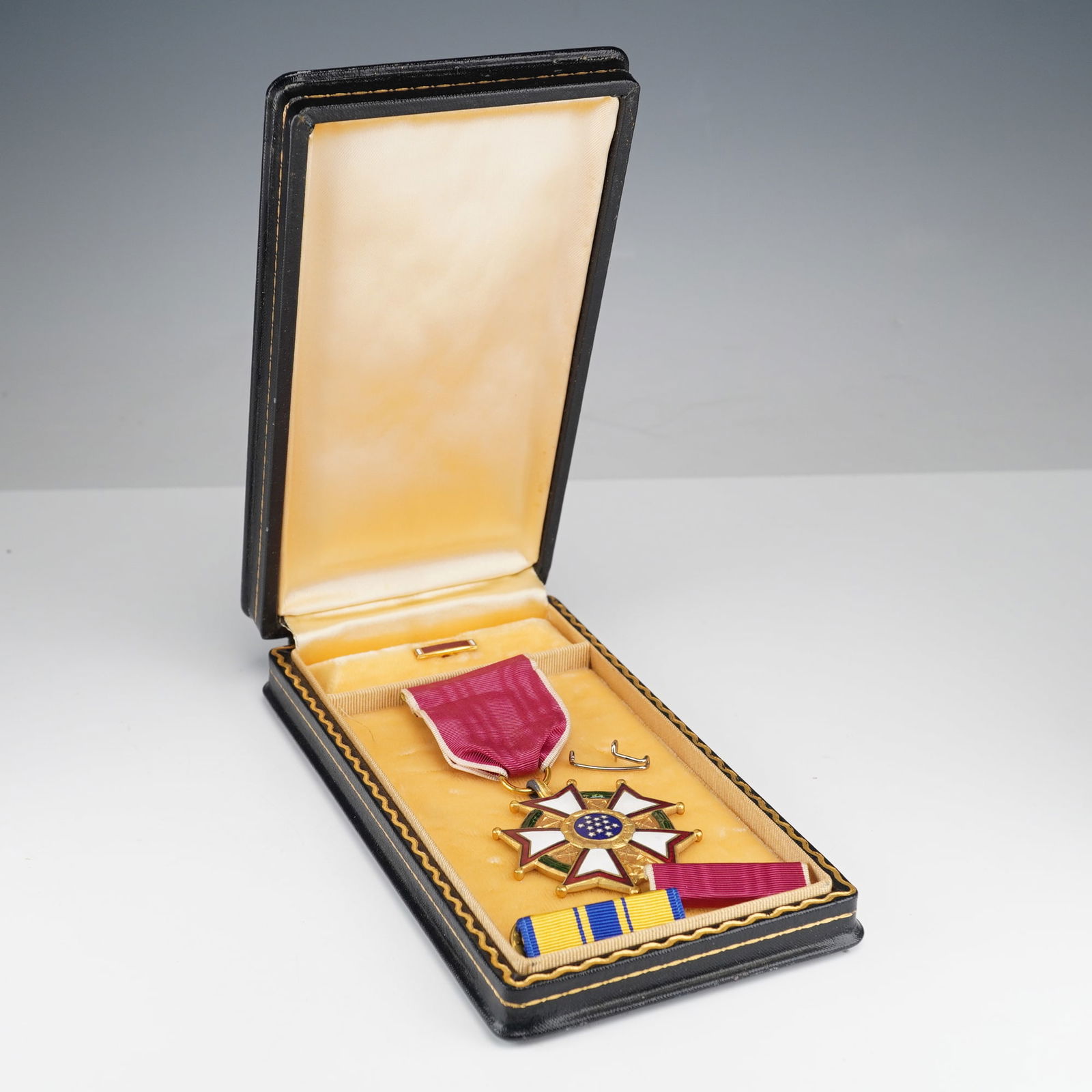 WWII US Legion of Merit Legionnaire Medal, Named to W.E. Thorne: A WWII Legion of Merit Legionnaire Medal named to W.E. Thorne. Gold'toned star with enamel details, crimson ribbon. Reverse inscribed UNITED STATES OF AMERICA, ANNUIT COEPTIS, NOVUS ORDO SECLORUM, MDC