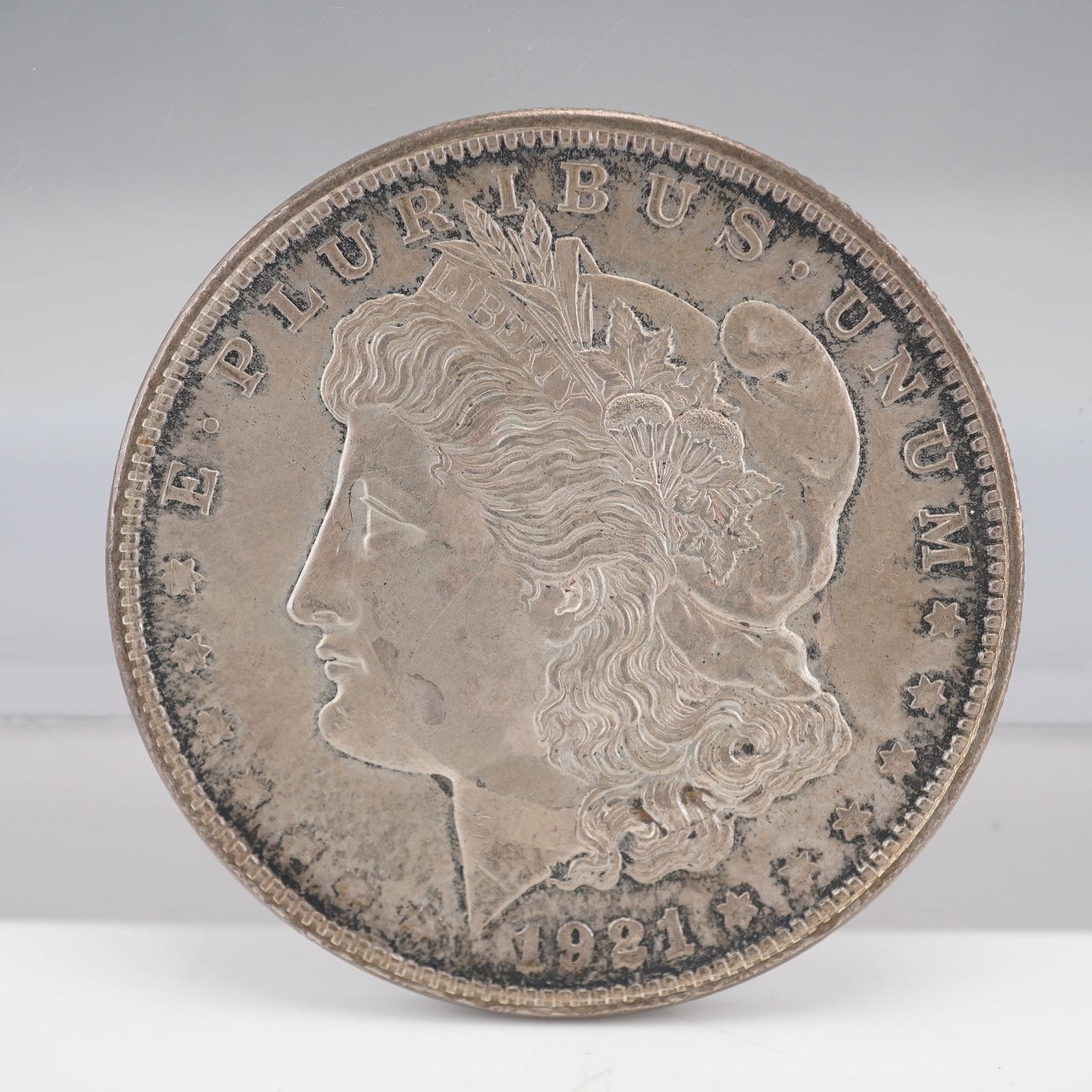 1921 Morgan Silver Dollar: A 1921 Morgan Silver Dollar. Obverse: Liberty with LIBERTY headband, 1921, E PLURIBUS UNUM. Reverse: Eagle with olive branch and arrows, UNITED STATES OF AMERICA, ONE DOLLAR, In God we trust. 