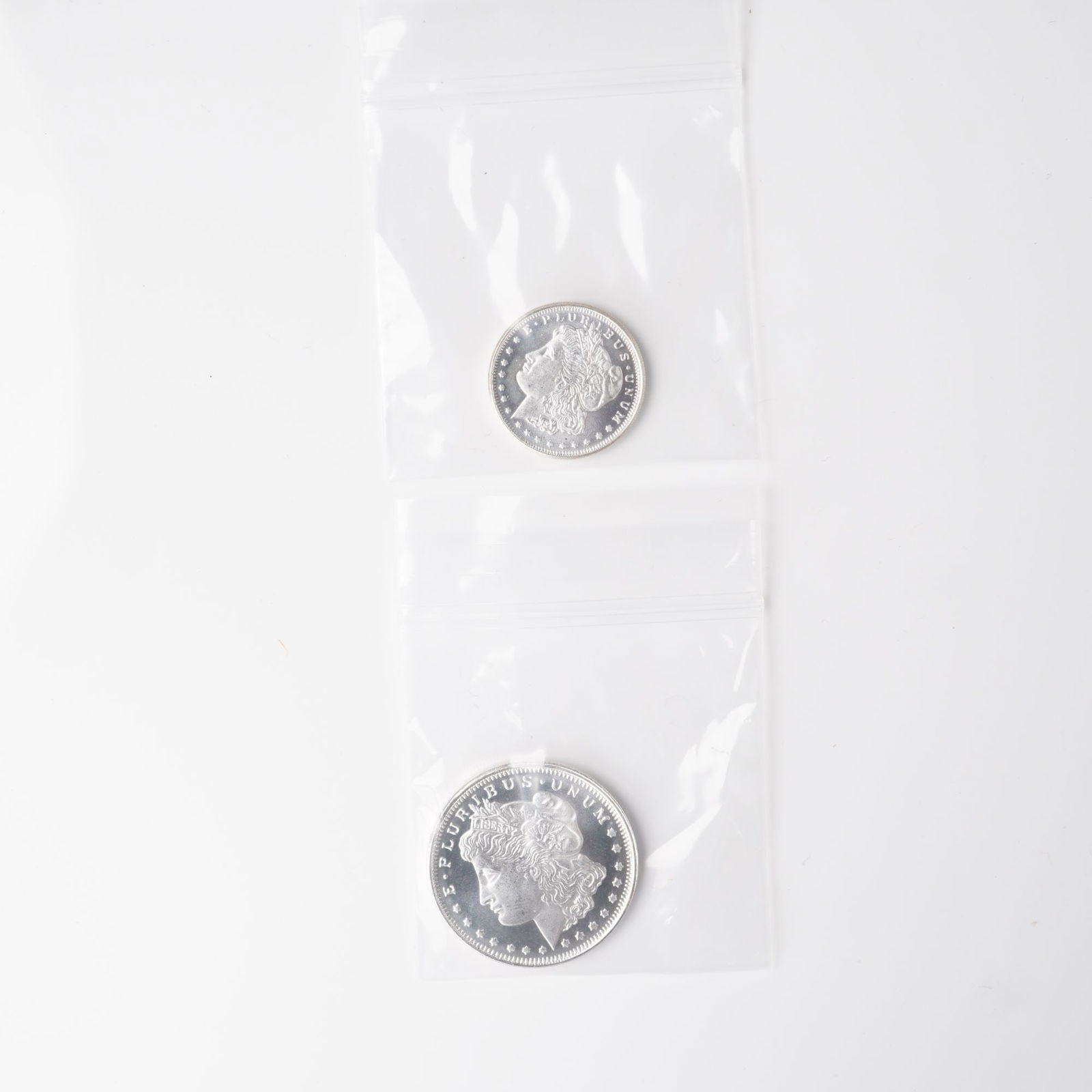 2pc 1/2 Troy Ounce and 1/4 Troy Ounce Morgan Silver Rounds: Two silver replica rounds inspired by the celebrated Morgan Dollar design. The obverse depicts the classical Liberty head profile crowned with a Phrygian cap, encircled by the inscription E Pluribus