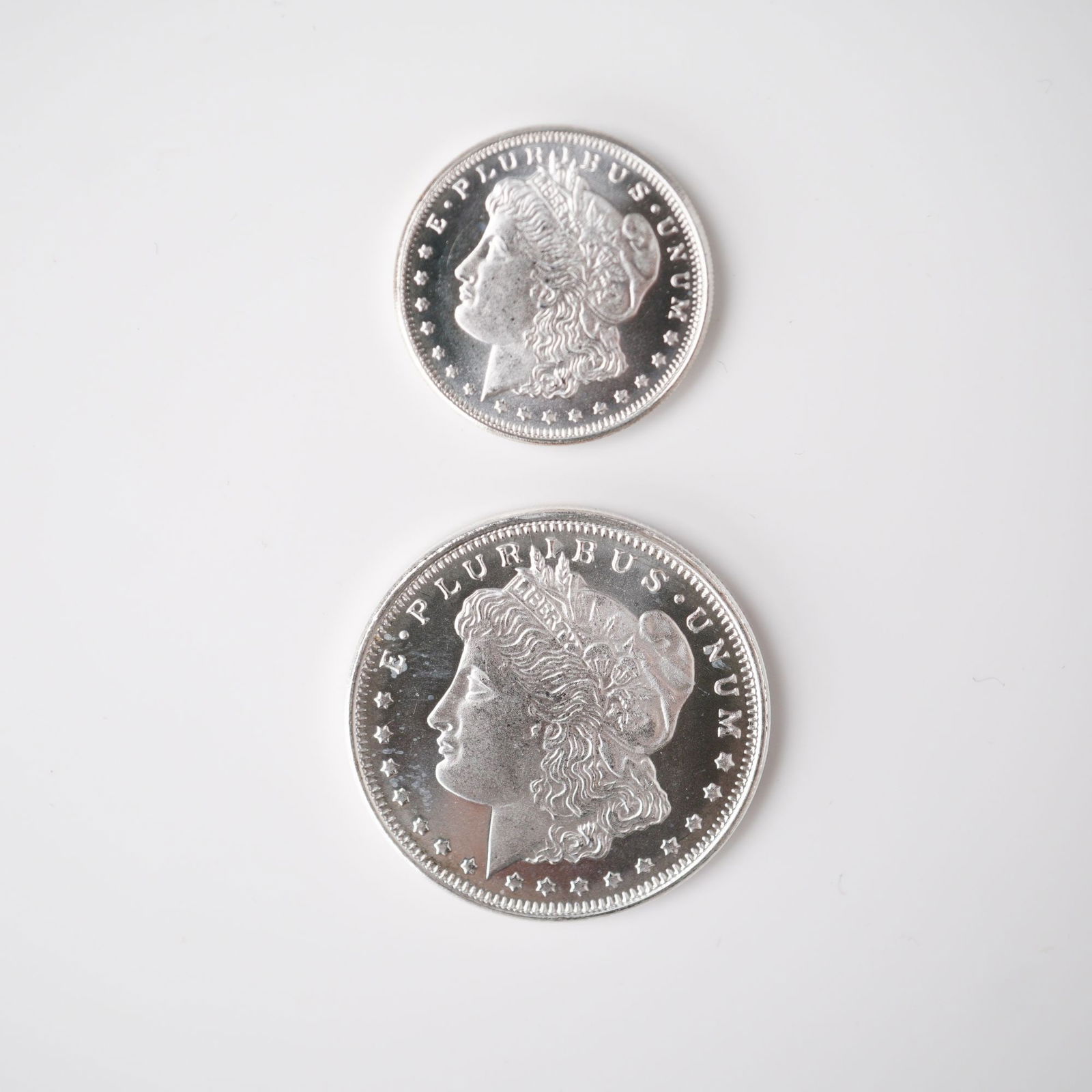 2pc Highland Mint Morgan Silver 1/2 and 1/4 Troy Ounce Coins: Two Highland Mint fractional silver coins, each struck in .999 fine silver and modeled after the classic Morgan Dollar design. This set includes one coin weighing one-quarter troy ounce and one coin