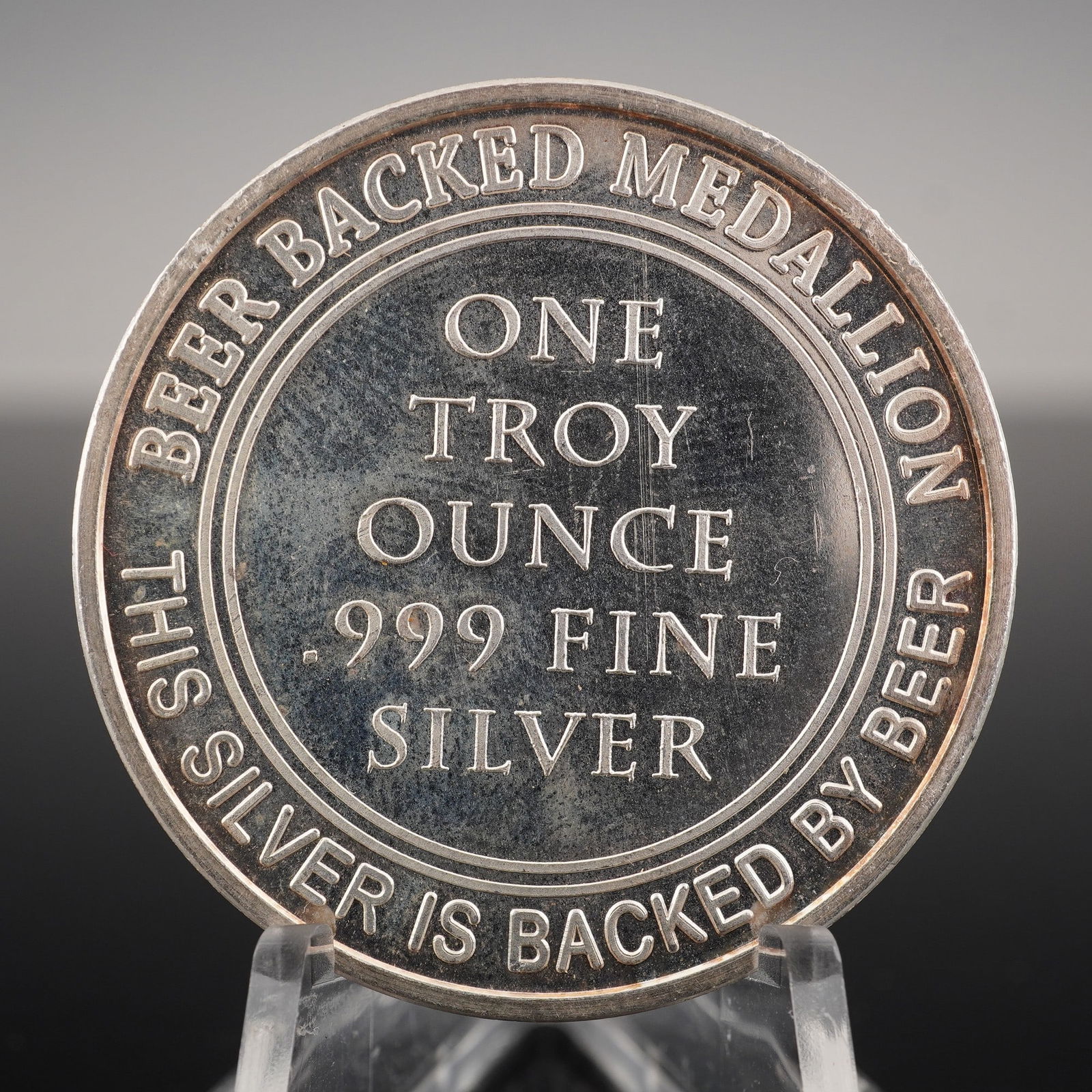 One Troy Ounce .999 Fine Silver Universal Beer Medallion: One side features the inscription BEER BACKED MEDALLION and THIS SILVER IS BACKED BY BEER surrounding the central text indicating weight and purity. The reverse displays a stylized beer mug with