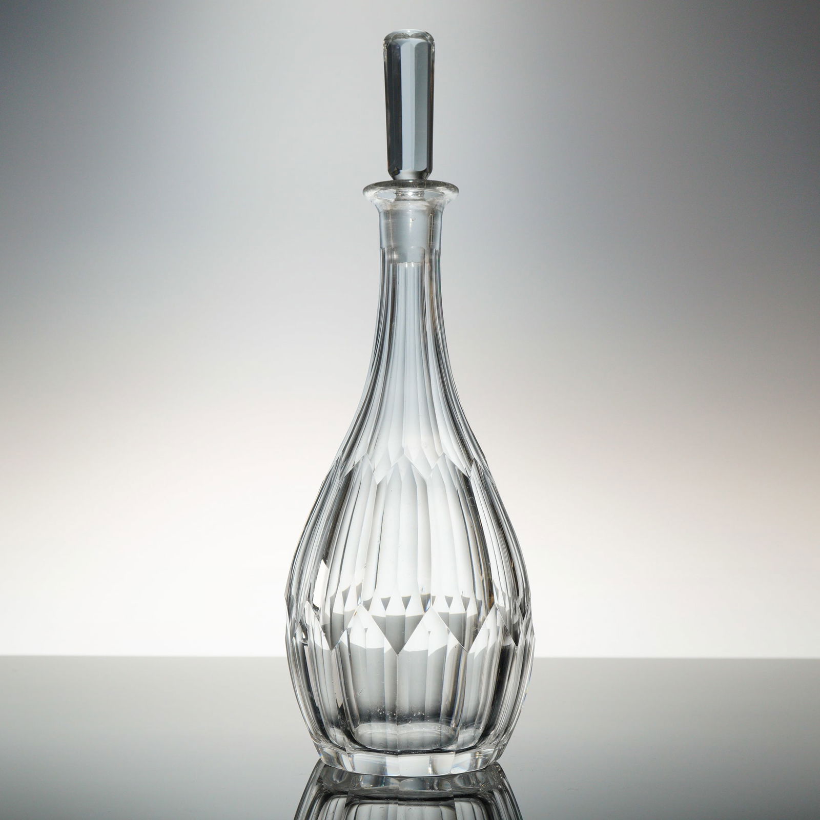 Orrefors Cut Crystal Decanter with Stopper: A two-piece set consisting of a colorless lead crystal decanter and its matching faceted stopper, atributed to the Swedish manufacturer Orrefors. The decanter features a globular body transitioning to