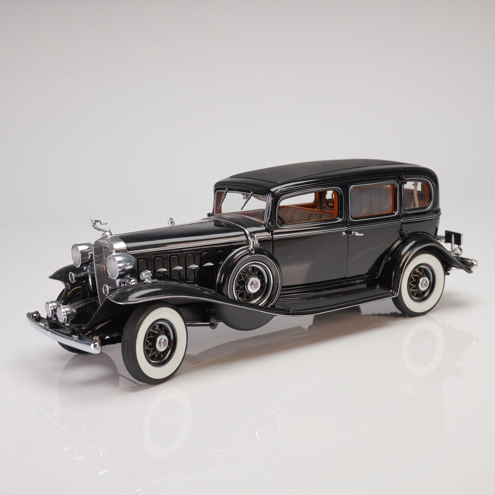 The Danbury Mint 1:24 Scale 1932 Cadillac V-16 Fleetwood Sedan Model: This lot presents a highly detailed 1:24 scale die-cast model replica of the iconic 1932 Cadillac V-16 Fleetwood Sedan, produced by The Danbury Mint. The model features a high-gloss black exterior fin