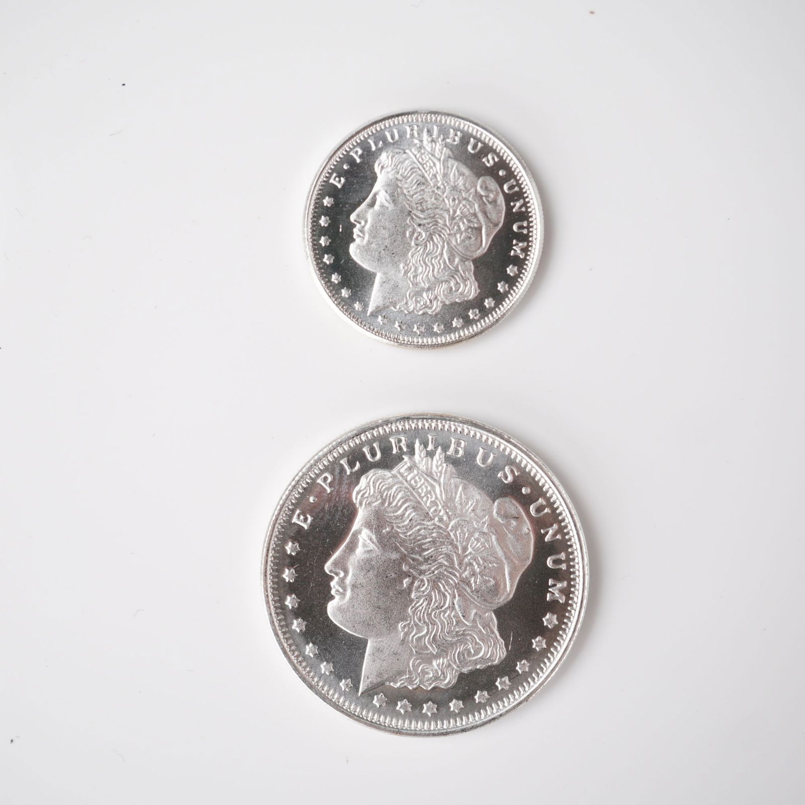 2pc Highland Mint Morgan Silver 1/2 and 1/4 Troy Ounce Coins: A 2-piece set of Highland Mint Morgan silver coins, comprising one half troy ounce and one quarter troy ounce coin, each struck in .999 fine silver. Both examples replicate the iconic Morgan dollar