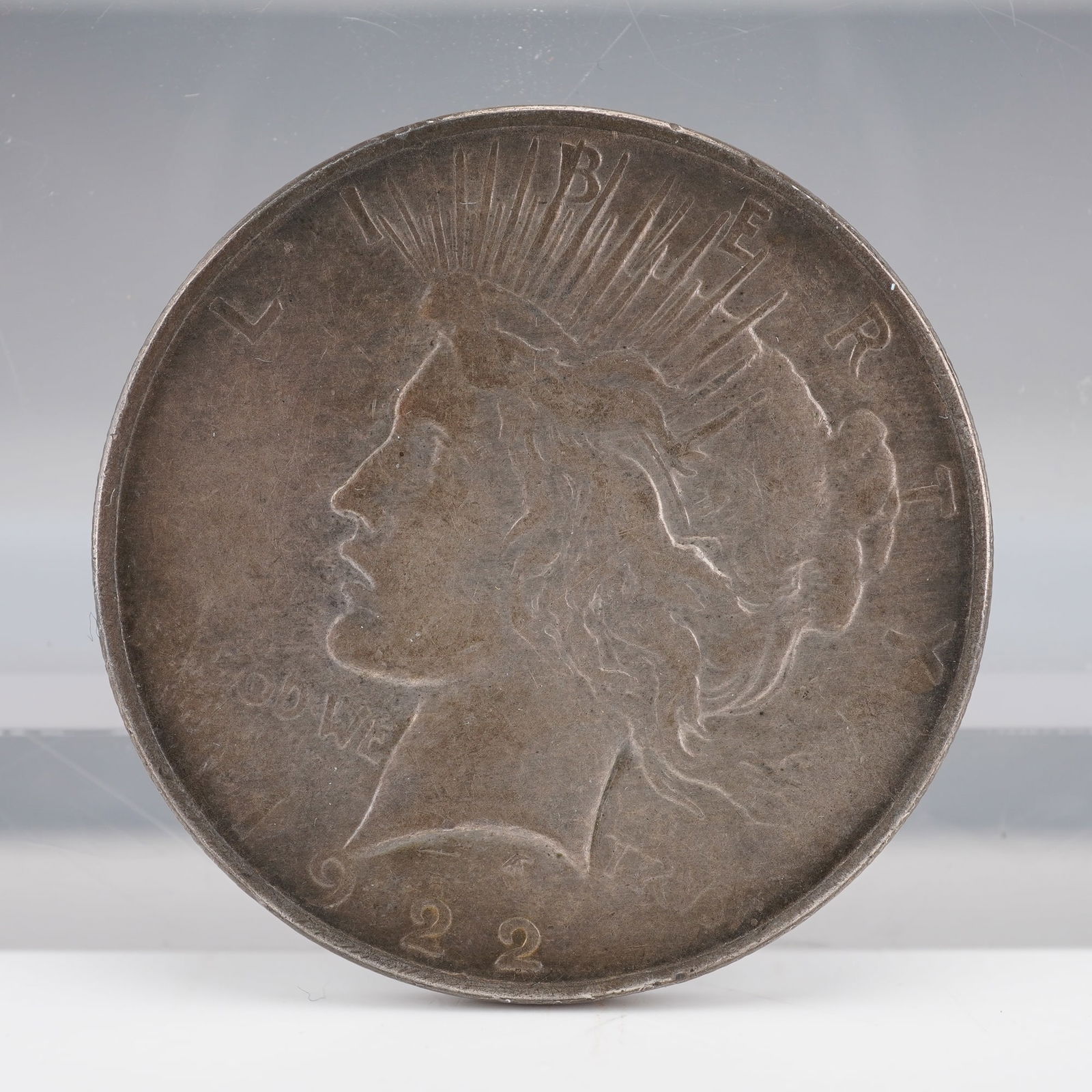 1922 United States Peace Silver Dollar: A 1922 Peace Silver Dollar. Obverse: Liberty with radiate crown, LIBERTY, IN GOD WE TRUST, 1922. Reverse: Eagle on rock with olive branch, UNITED STATES OF AMERICA, E PLURIBUS UNUM, ONE DOLLAR,