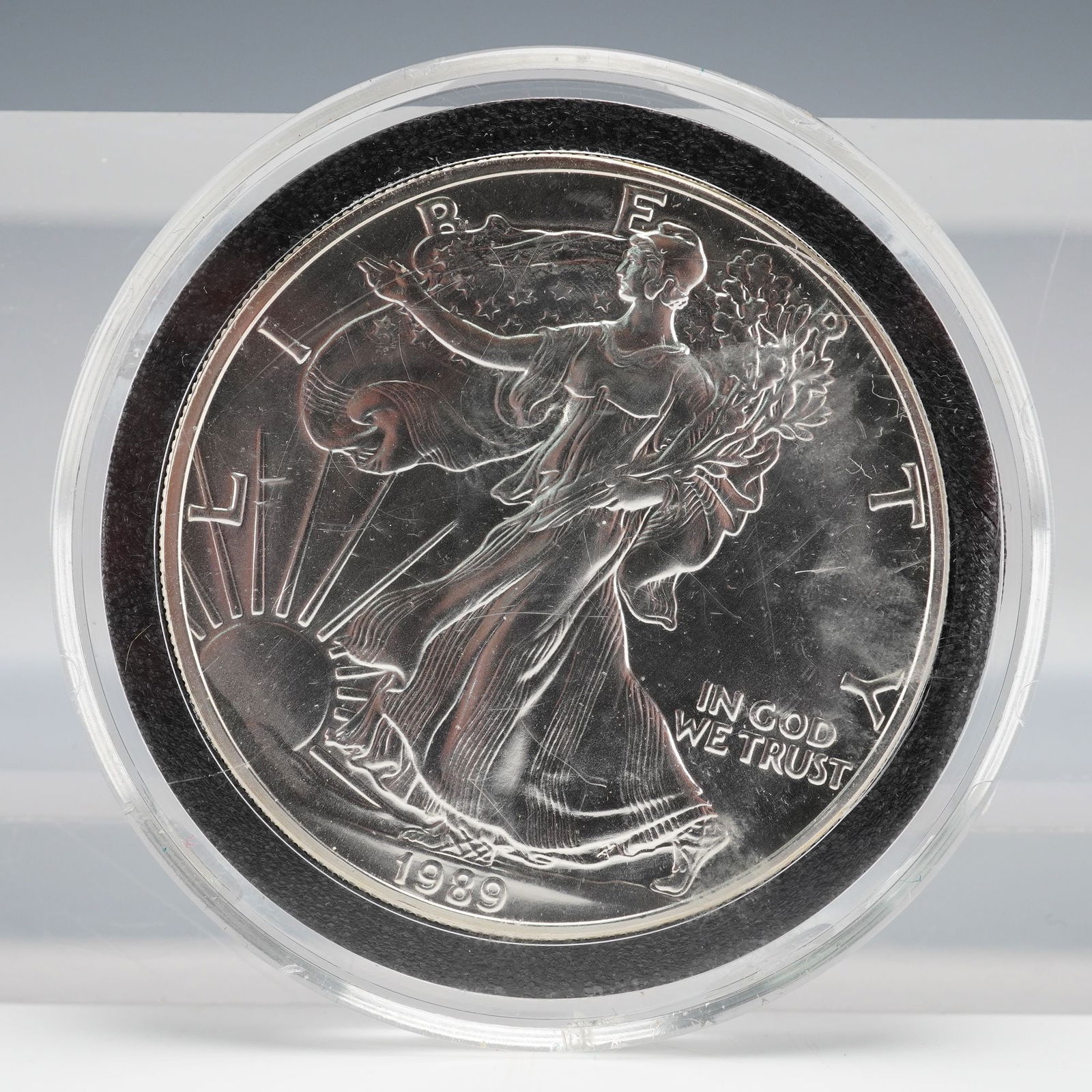 1989 American Silver Eagle Proof, 1 oz: A 1989 1 oz American Silver Eagle Proof in clear capsule with black foam insert. Obverse: Walking Liberty, LIBERTY, 1989, IN GOD WE TRUST. Reverse: Heraldic Eagle with shield, UNITED STATES OF