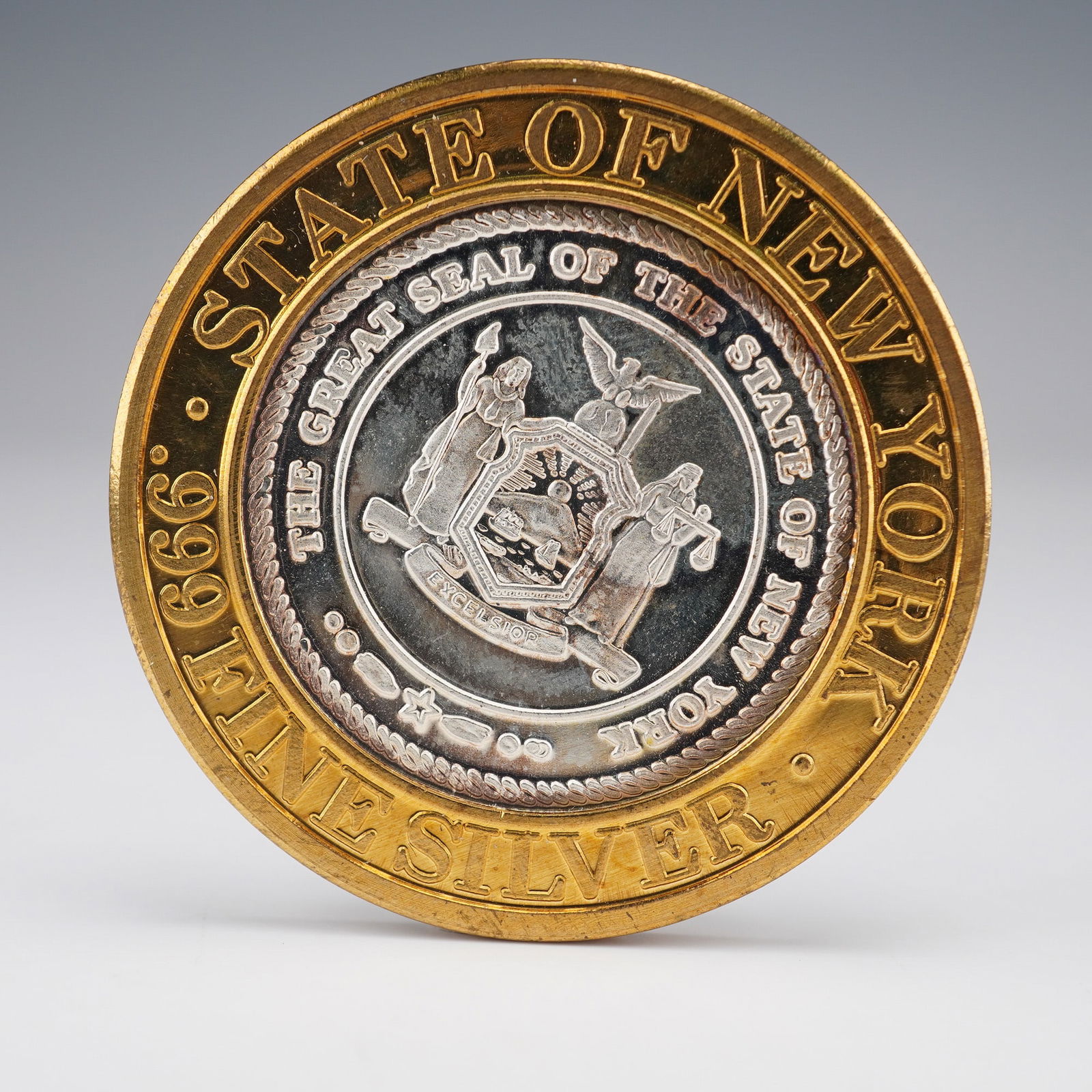 1994 Foxwoods Resort New York .999 Silver Token: This bi-metallic token features a gold-toned outer ring and a silver-toned core. The obverse displays the Great Seal of the State of New York in its center, encircled by the text "THE GREAT SEAL OF