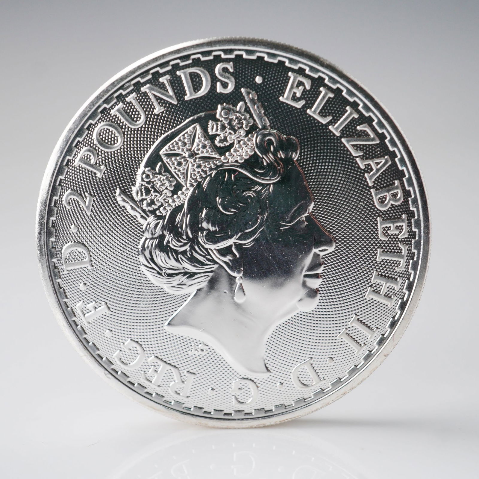 2023 British Britannia Coin 2 Pounds Elizabeth II 5th Portrait: This 2023 British Britannia 2 pound coin features the fifth crowned portrait of Queen Elizabeth II on the obverse, wearing the George IV State Diadem. The inscription reads Elizabeth II Dei Gratia