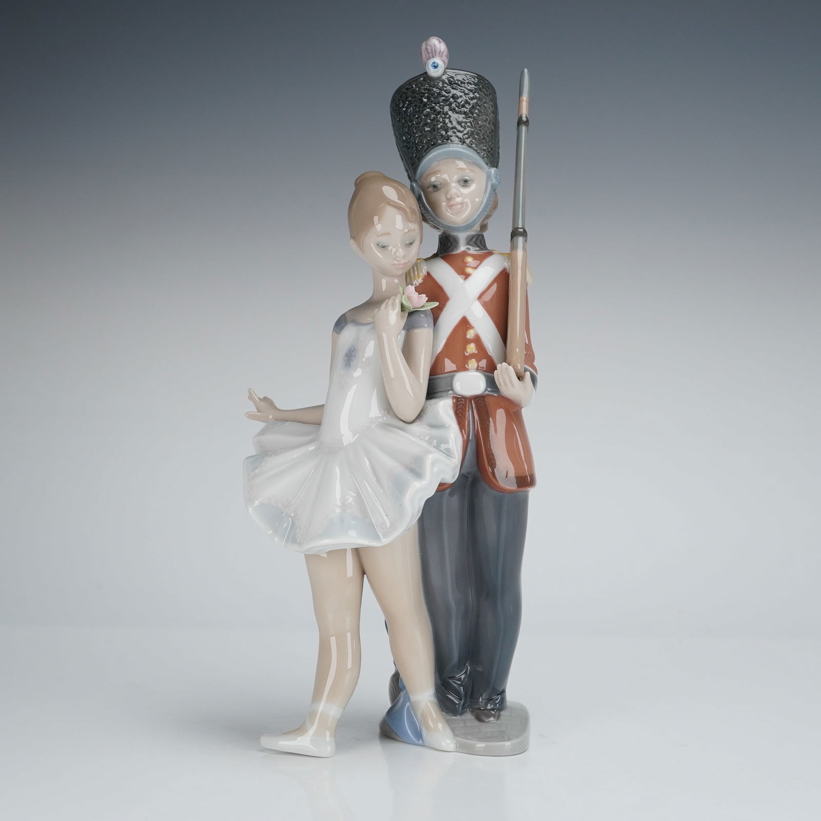 Lladro Privilege Gold Porcelain Figurine, Little Tin Soldier (01008321): The glazed porcelain piece depicts a scene inspired by Hans Christian Andersen's, featuring a ballet dancer embracing a toy soldier. The ballerina is rendered in a white tutu, holding a rose. The sold