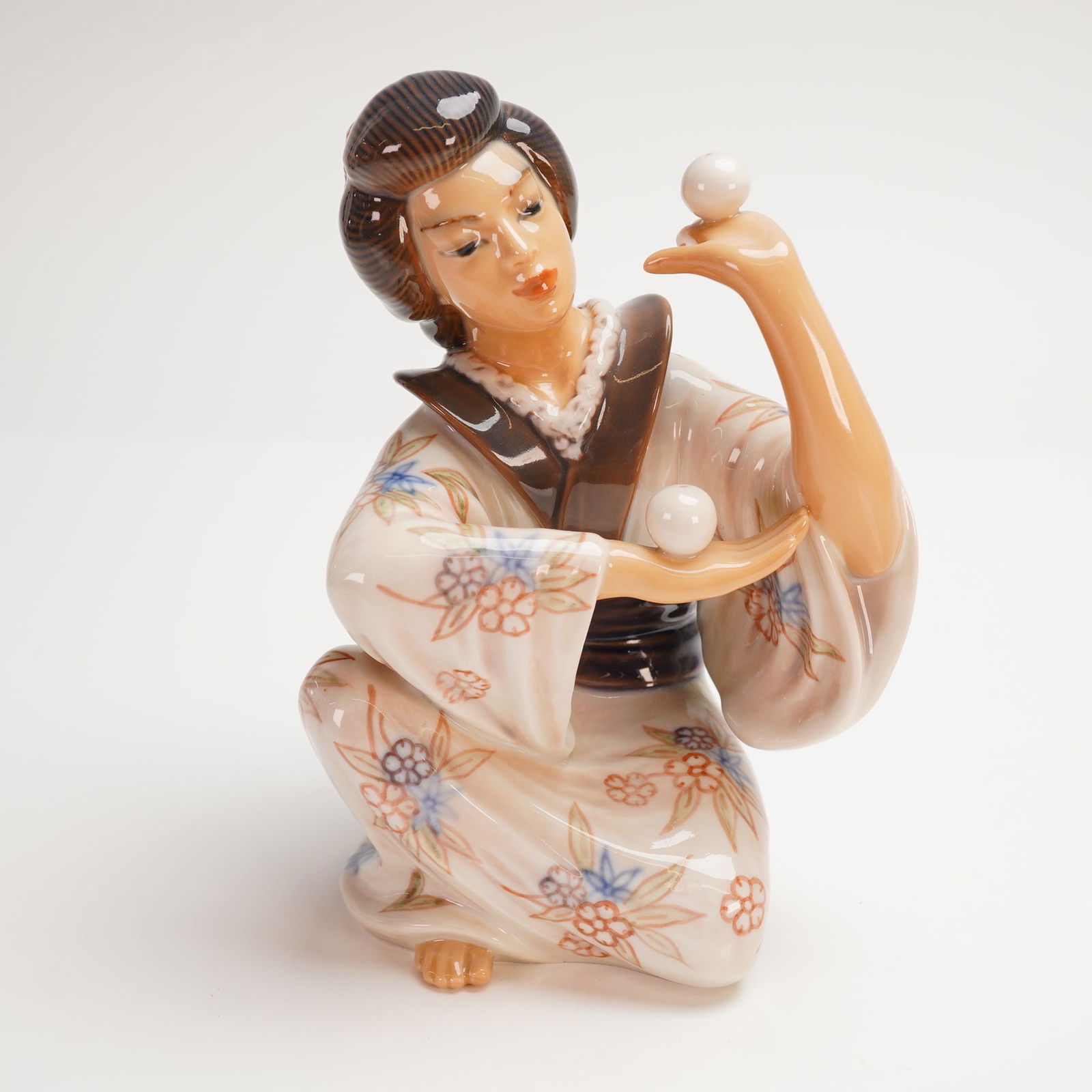 Dahl Jensen Porcelain Figurine, Japanese Juggler: A Danish porcelain figure depicting a Japanese woman performing a balancing act with two small white spheres. Marked on the underside with the Dahl Jensen backstamp and model no. 1326. Dimensions: 5.2
