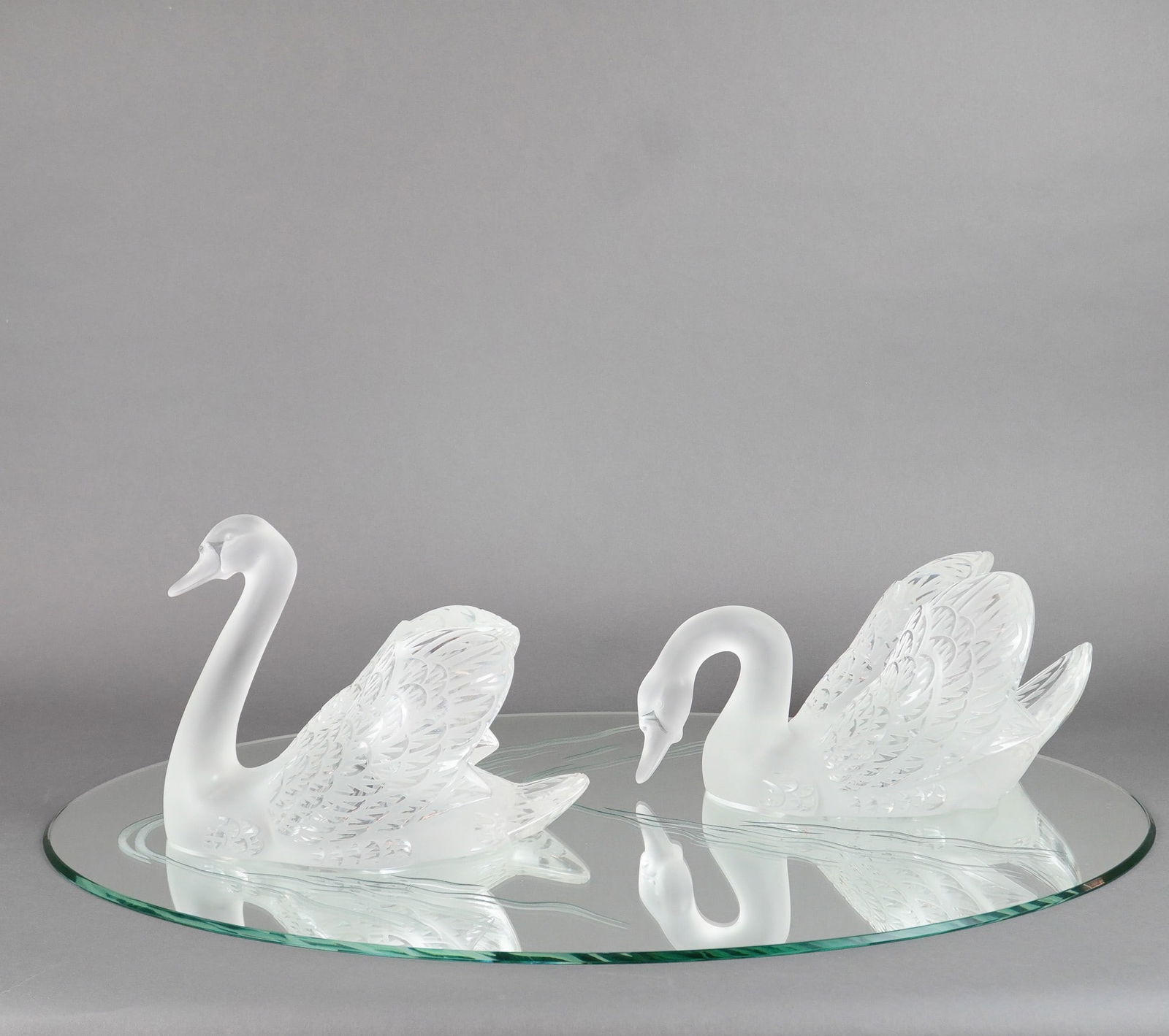 Lalique Miroir Cygnes Swans Centerpiece on Mirror Base: Lalique's Miroir Cygnes is a splendid set made of two large crystal swan sculptures and an oval mirror glass display base. The swans are executed in the signature Modernist style of Lalique, utilizing