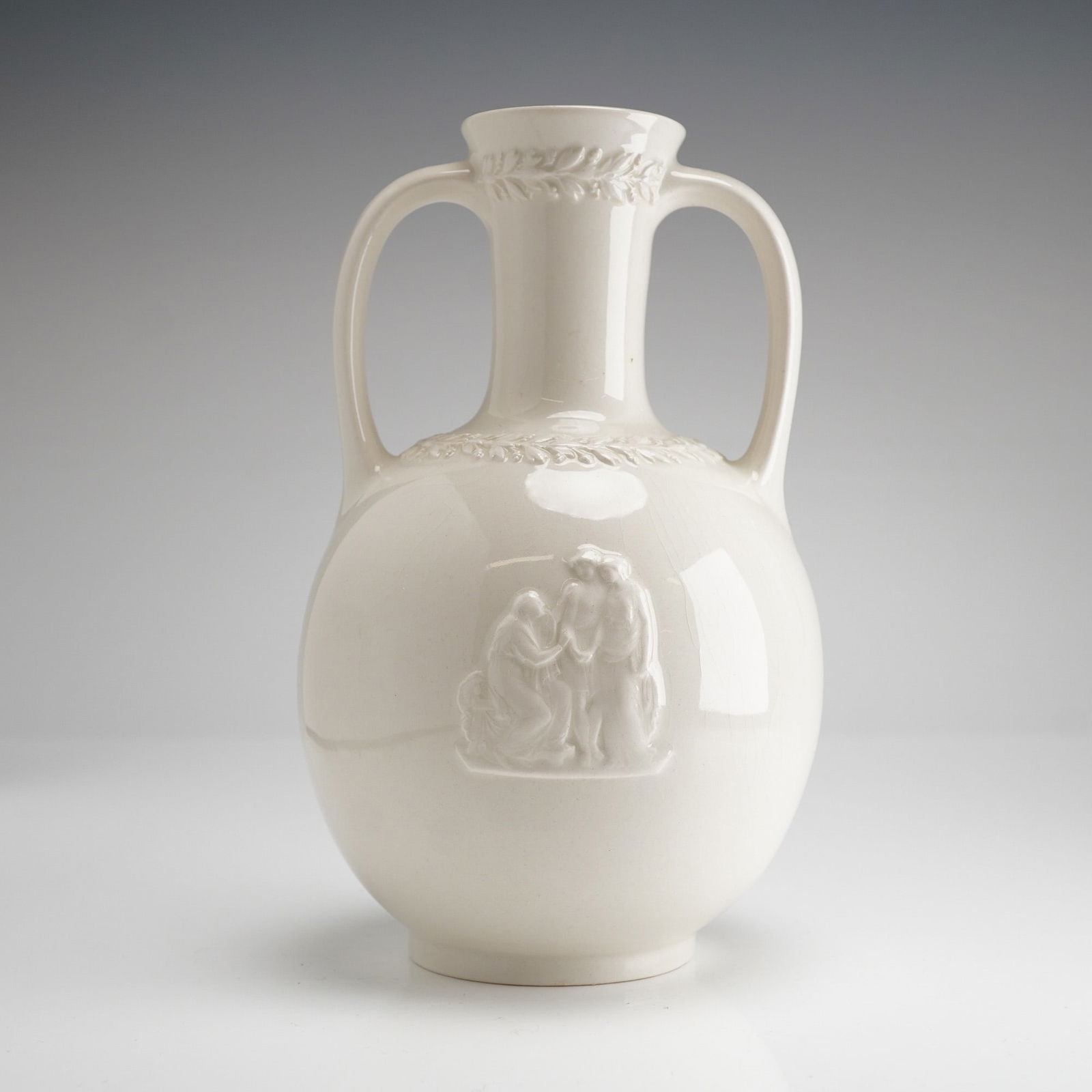 Wedgwood of Etruria & Barlaston Queensware Amphora Vase: Crafted from cream-colored glazed ceramic in the Neoclassical style. The amphora-form vessel features a globular body and two looped handles. Decoration includes applied bas-relief molding, consisting