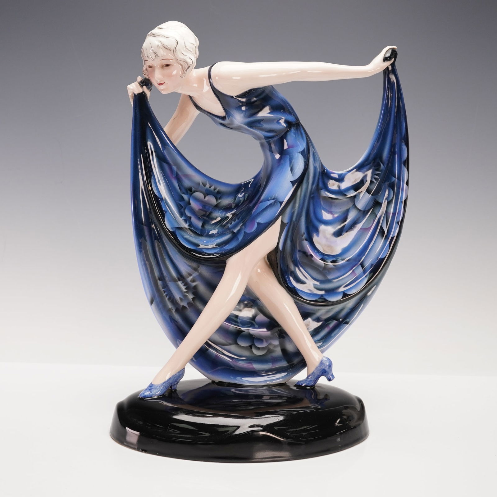 Goldscheider Josef Lorenzl Figurine, Art Deco Female Dancer: Modelled as a female dancer, her back arched, with arms outstretched holding out her long skirt, painted with flowers against a royal blue ground, on a black oval base. Model no. 6227. Goldscheider ba