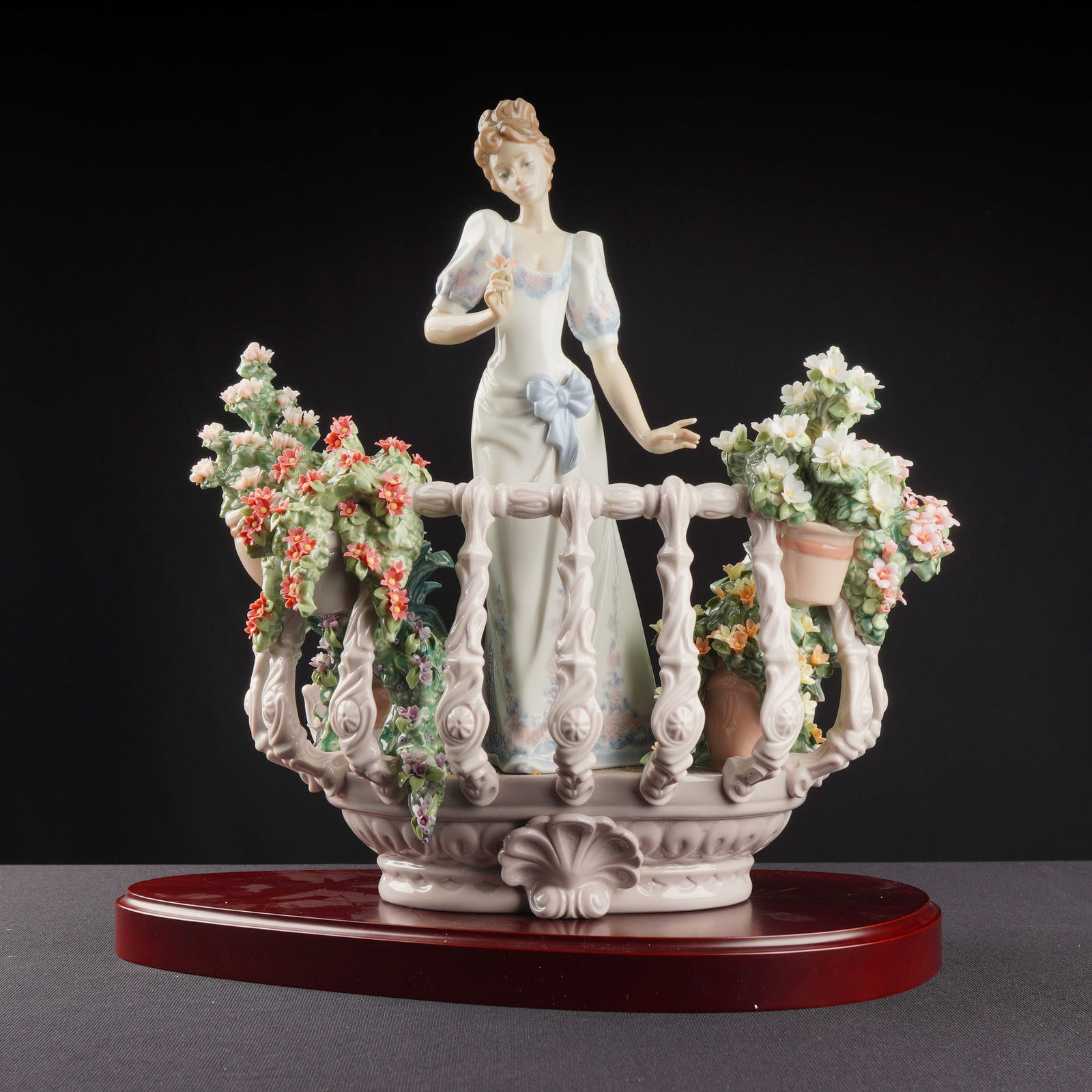Lladro Porcelain Sculpture Far Away Thoughts 01001798 with Base: The limited edition Lladro porcelain sculpture titled Far Away Thoughts, Model No. 01001798, also known by the Spanish title Flores en el Balcon. The sculpture depicts an elegant female figure in a wh