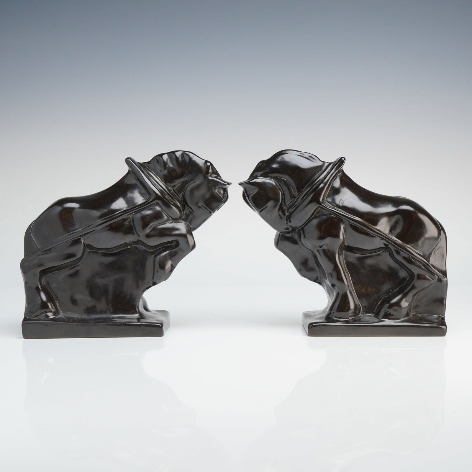 Pair of Wedgwood Black Ceramic Horse Bookends: Circa 1930s, a pair of ceramic bookends each modeled as a stylized horse wearing a horse collar, depicted in a stance suggesting it is pulling a heavy load. The ceramic bookends are finished in a