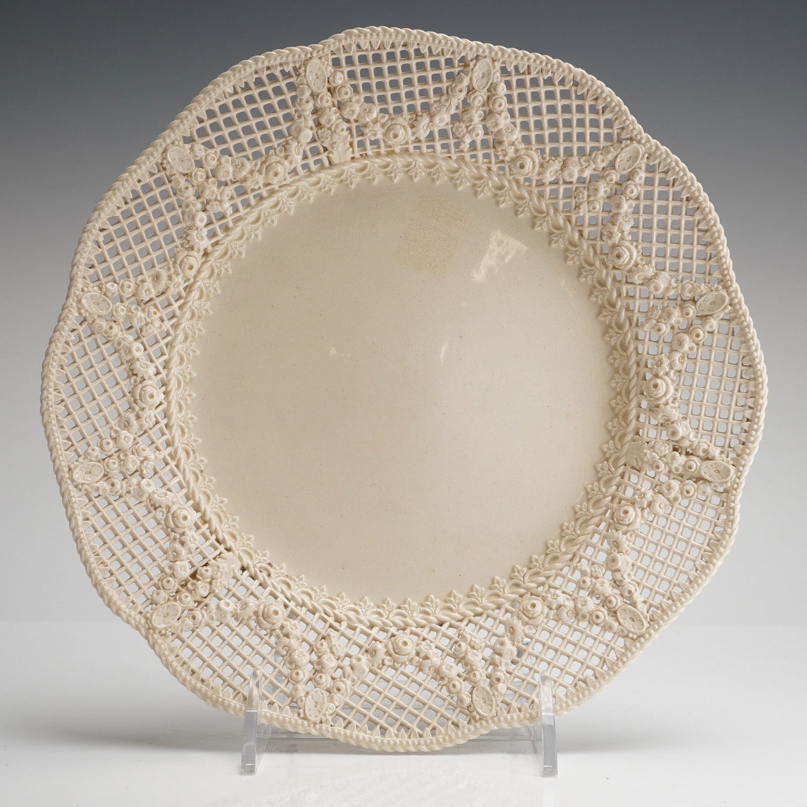 Wedgwood Ceramic Creamware Reticulated Lace Plate: A circular creamware plate manufactured by Wedgwood. The plate features a wide, pierced reticulated rim, often referred to as a lace plate, decorated with molded floral and foliate relief elements sur