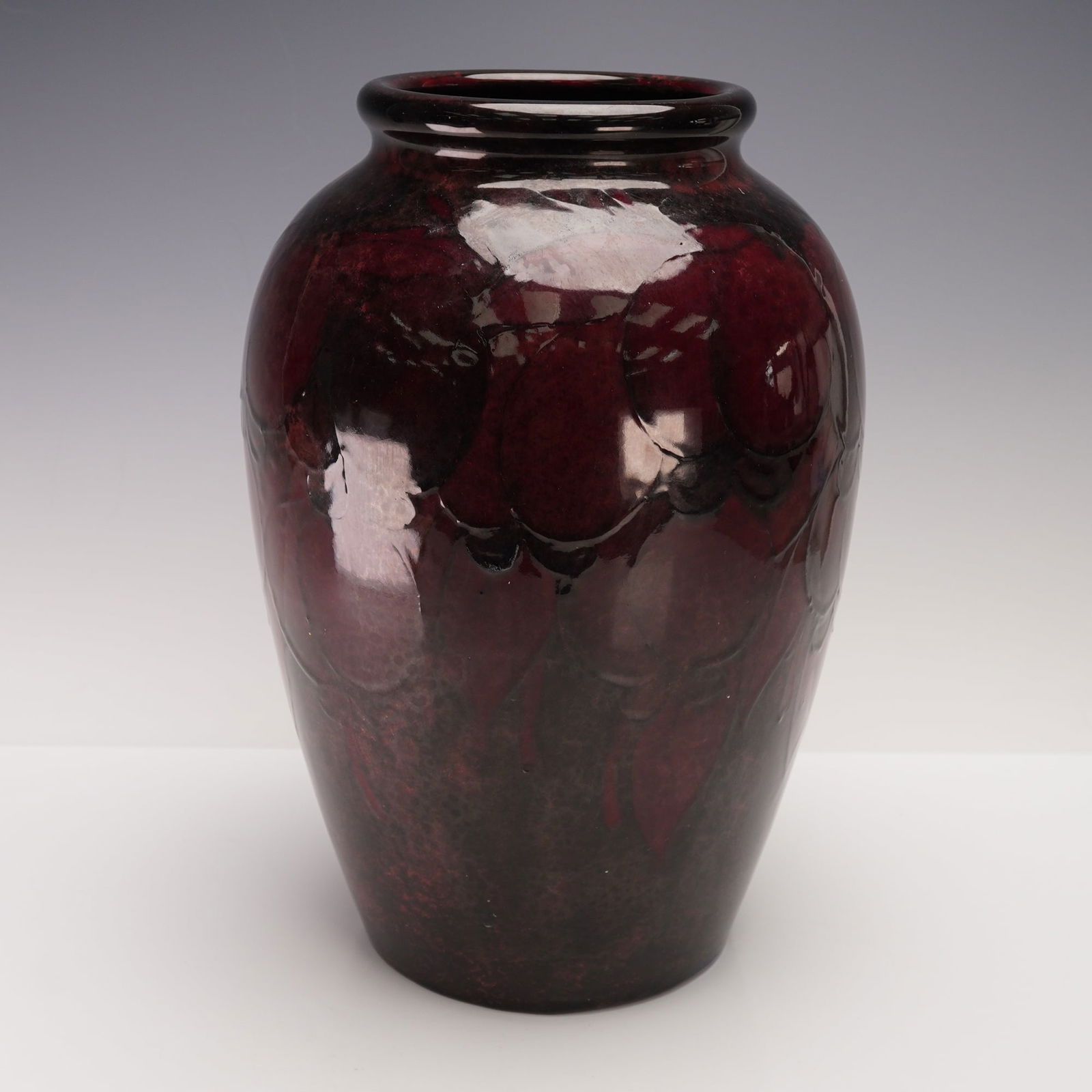 William Moorcroft Flambe Vase, Wisteria: A very early striking vessel pattern beneath a rich flambe glaze, the tube-lined pendant fruit and foliage design subtly visible through layers of deep oxblood and plum-red glaze. Signed "W