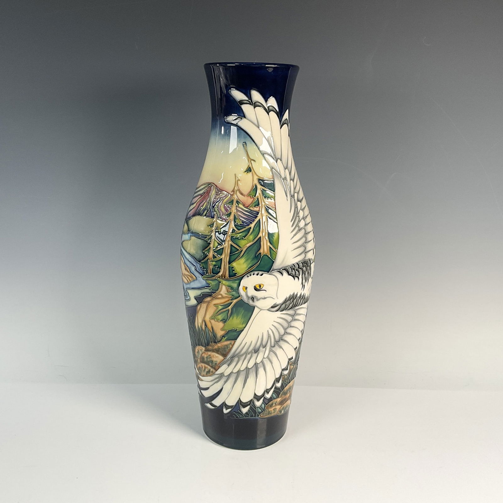 Moorcroft Limited Edition Vase, Mountain Kingdom, Owls: Stunning tall slender vase of a flying white owl on a vibrant cobalt blue, green, pale yellow and tan woodland background. Moorcroft stamp. Signed Philip Gibson. Artist: Philip Gibson Dimensions:
