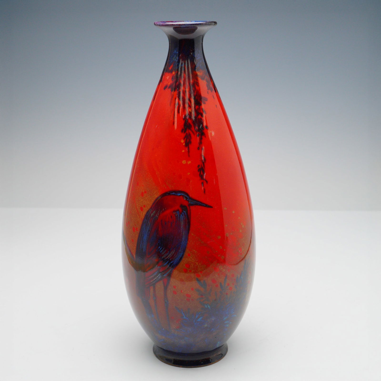 Royal Doulton Flambe Sung Bird Vase: Tall, narrow-shouldered flambe glazed porcelain vase by Royal Doulton, featuring a stylized depiction of a wading bird, possibly a heron or crane, rendered in deep cobalt blue and purple against a viv