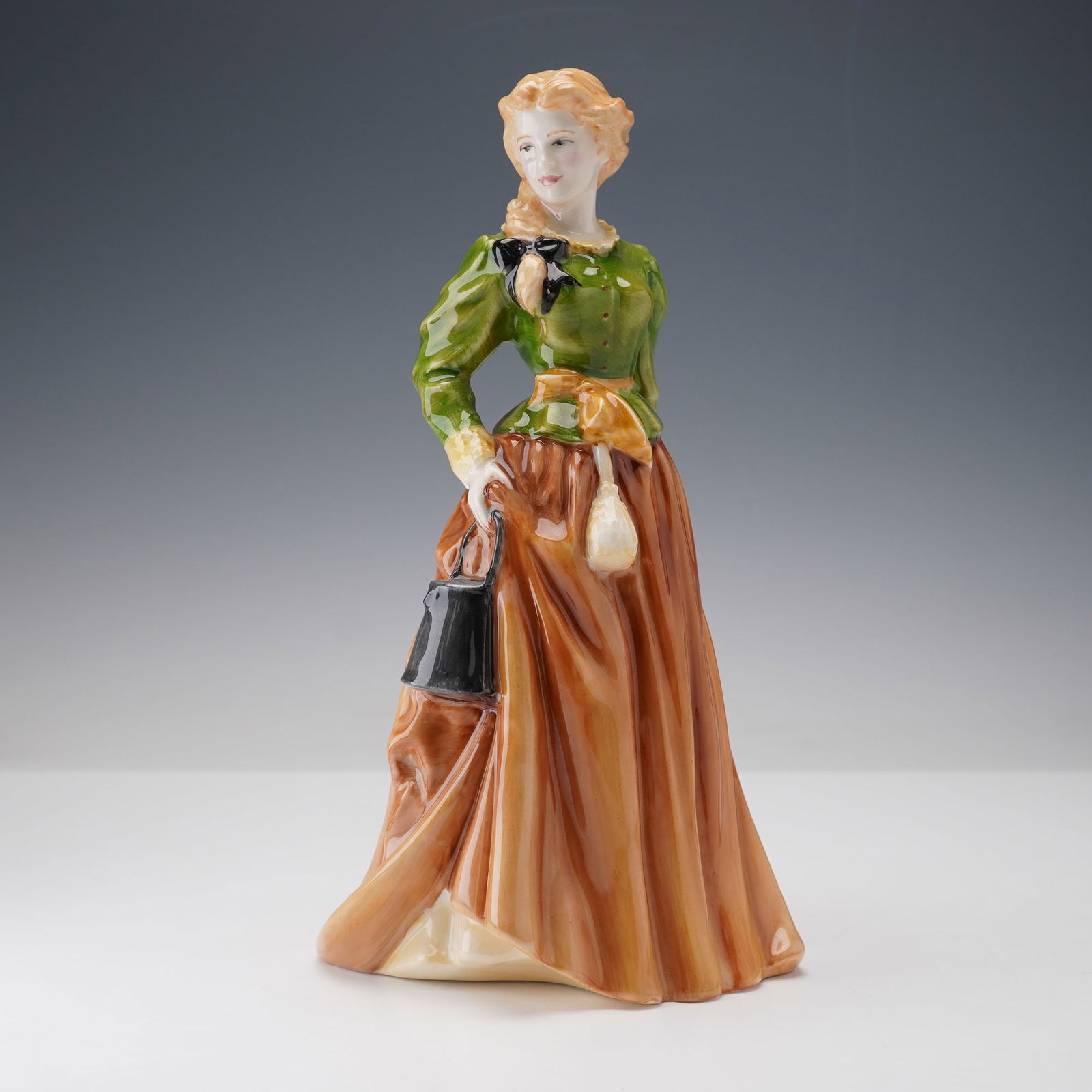 Prototype Royal Doulton Figurine, Maid with Bucket: This Royal Doulton prototype figurine depicts a maid in traditional attire, elegantly portrayed with a flowing green blouse and light brown skirt. Her long, braided blonde hair falls gently over one