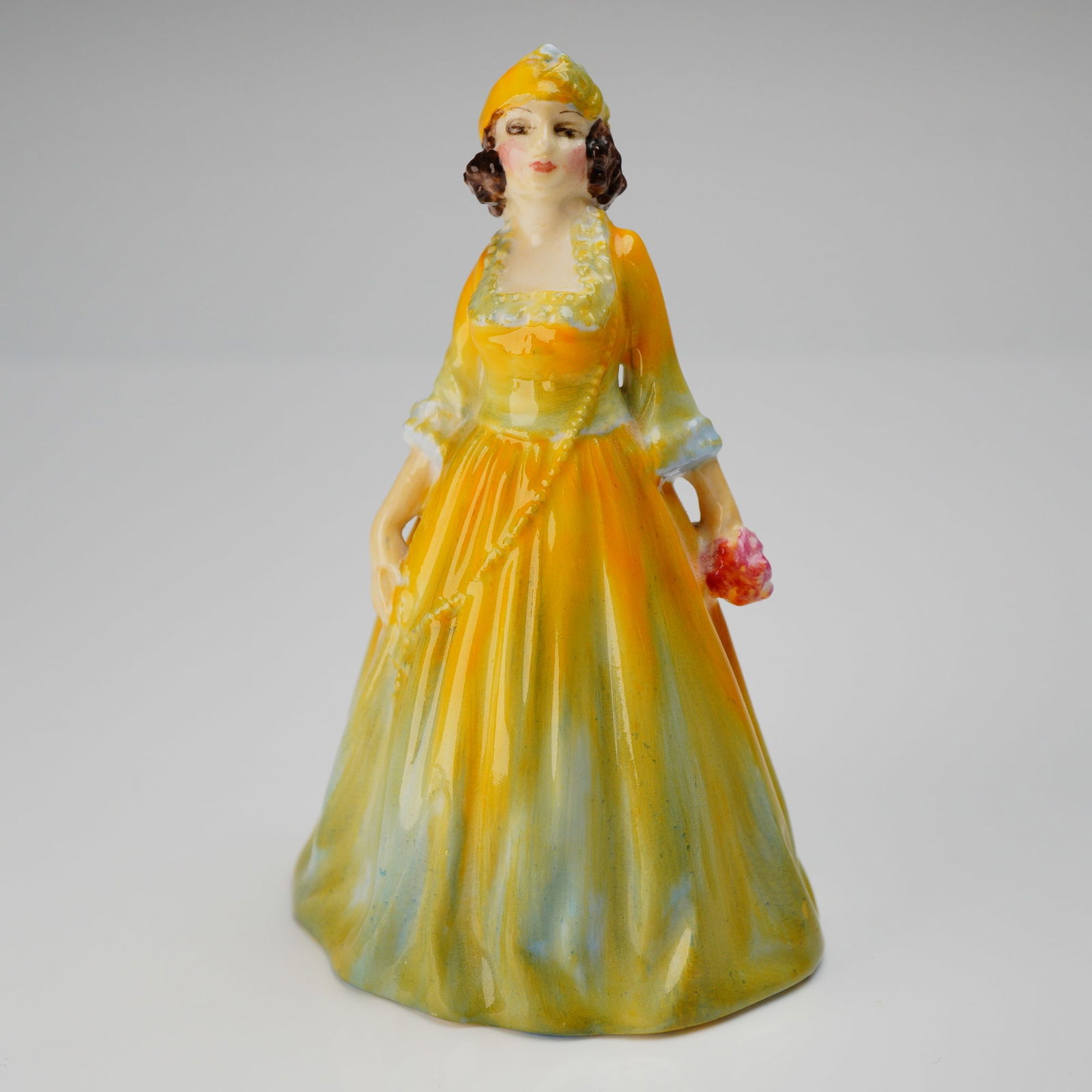 Royal Doulton Miniature Figurine, Rosamund M32: A single glazed porcelain figurine identified as the miniature figure Rosamund, model number M32. The figure depicts a standing female figure dressed in a formal period-style gown and bonnet,