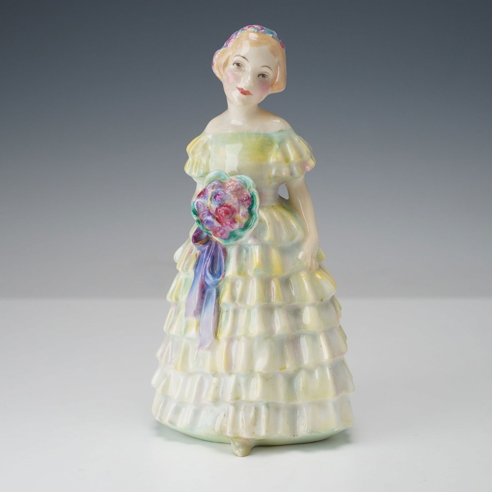 Royal Doulton Figurine, The Little Bridesmaid HN1434: A Royal Doulton figurine, The Little Bridesmaid HN1434, designed by Leslie Harradine and produced between 1931 and 1949. The figure depicts a young girl in an off-the-shoulder tiered dress holding a