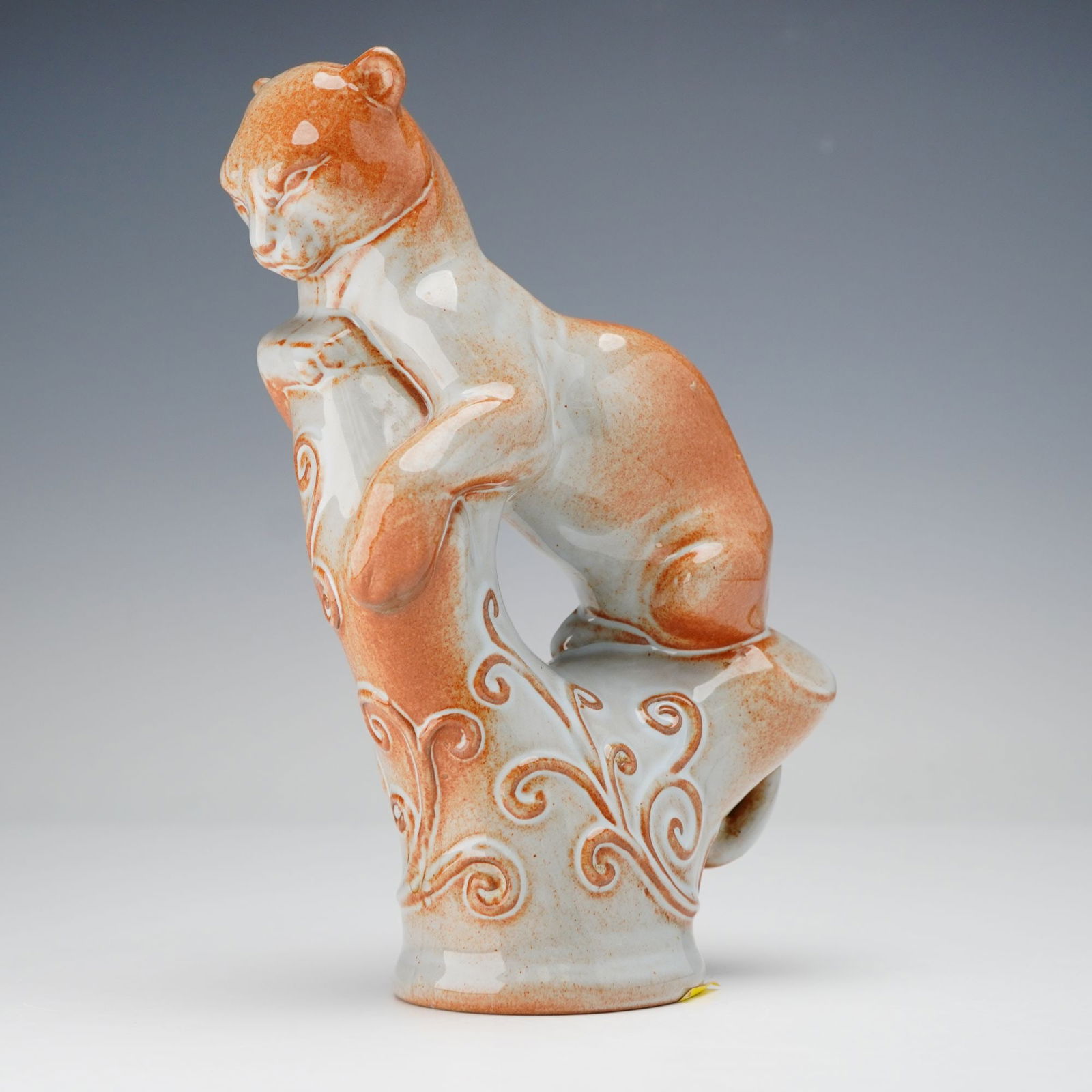 Wedgwood by Arnold Machin Brown and Gray Glaze Leopard Figure: A rare Wedgwood glazed ceramic figure depicting a leopard perched in a watchful pose on an ornate, scrolling tree-stump support. The piece is finished with a brown and grey glaze with areas of the sup