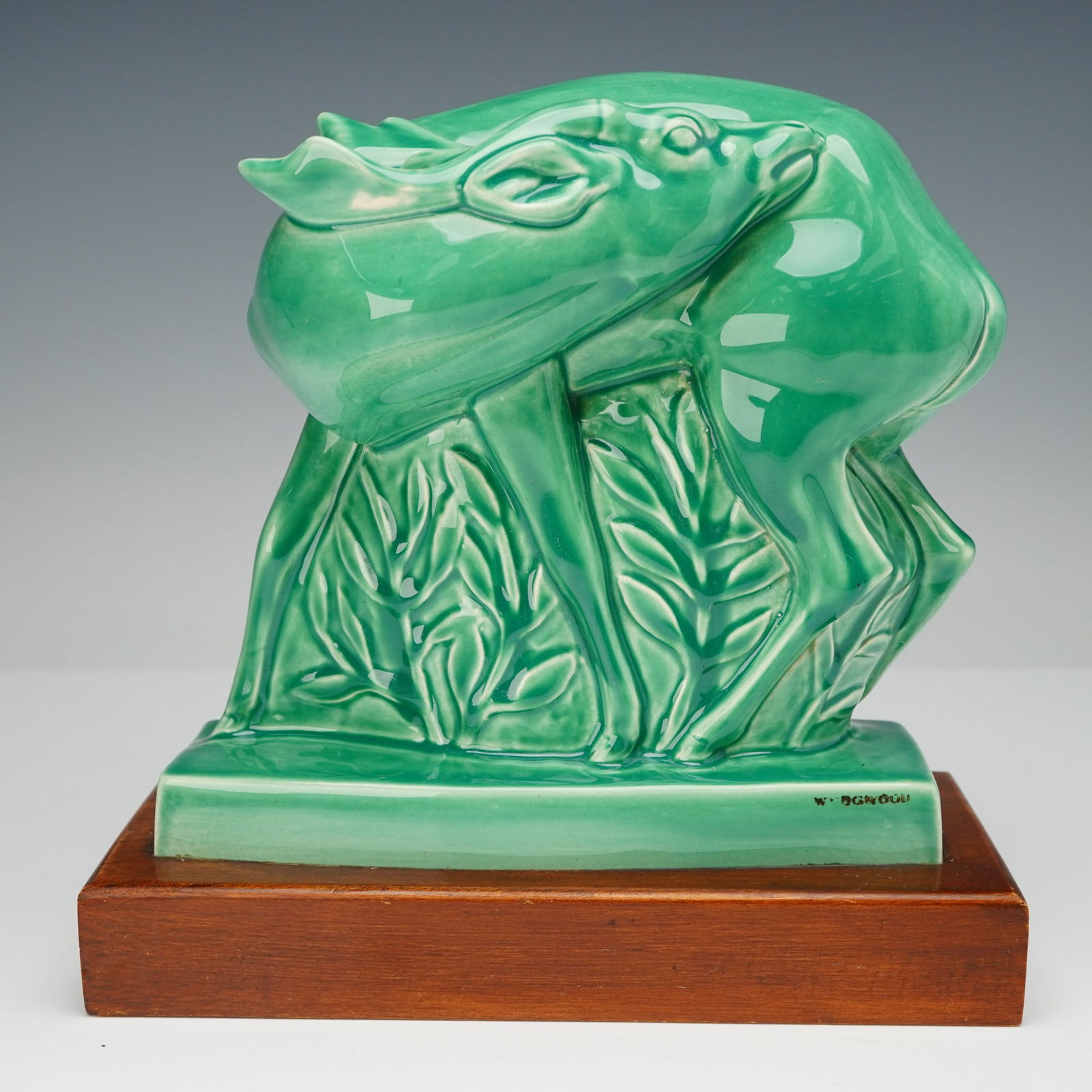 Wedgwood by John Skeaping Green Glazed Ceramic Art Deco Deer Figurine: A glazed ceramic figure of a fallow deer, designed by John Skeaping for Wedgwood, embodying the Art Deco aesthetic. The stylized deer is depicted standing amidst foliage, presented in a green finish a