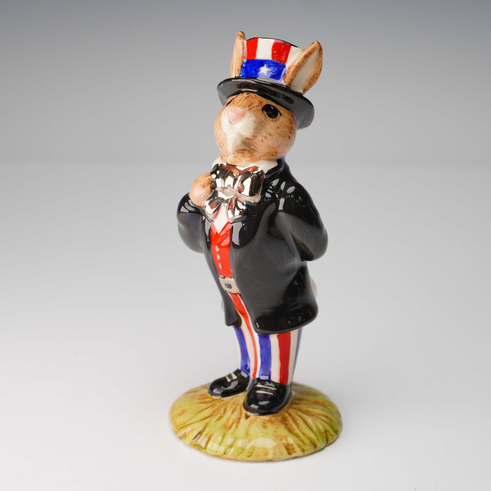 Royal Doulton Prototype Colorway Bunnykins, Uncle Sam DB50: A colorway bunnykins modeled in black coat, red vest, blue and red stripped pants and patriotic hat. Finished with a silver bow and belt buckle. Prototype backstamp. Royal Doulton backstamp. Artist: