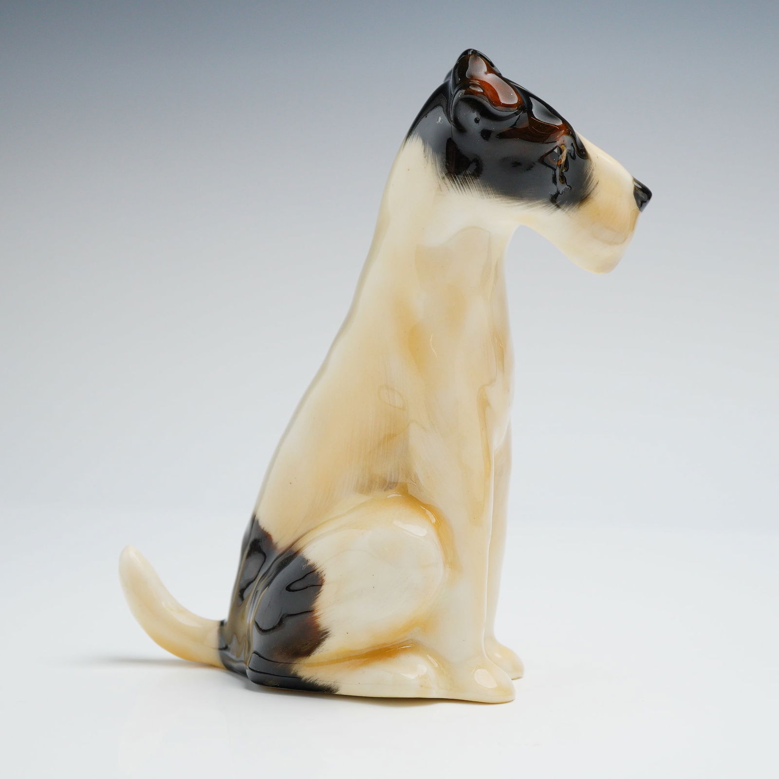 Royal Doulton Glazed Earthenware Seated Wire Fox Terrier Figurine HN910: A single glazed ceramic figurine attributed to Royal Doulton, depicting a seated Wire Fox Terrier in a naturalistic pose. The figurine is executed in glazed earthenware or porcelain, decorated in a