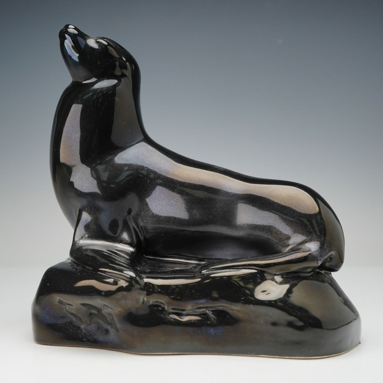 Wedgwood by John Skeaping Black Luster Glaze Sea Lion Figure: A rare Wedgwood black-glazed ceramic sculpture of a sea lion, modeled by John Skeaping in 1953. The figure depicts a stylized sea lion or seal in a rearing pose, rendered in a high-gloss, iridescent