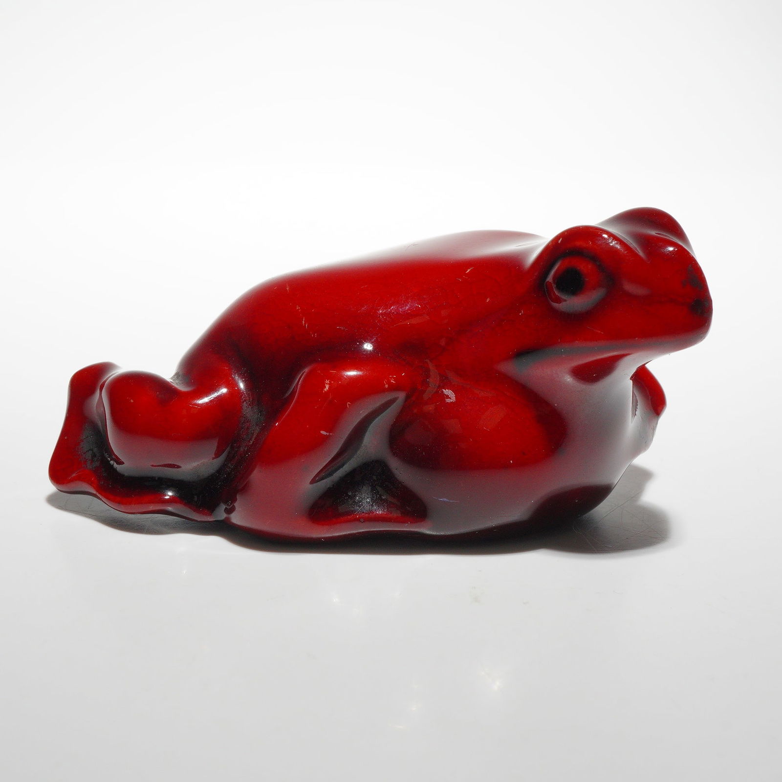 Royal Doulton Flambe Figurine, Frog: Rich red glaze with black highlights. Depicts an early model of a seated frog; model no. 1162B. "1162" inscribed to the bottom. Royal Doulton backstamp. Dimensions: 3"L x 1.75"W x 1.5"H Country of