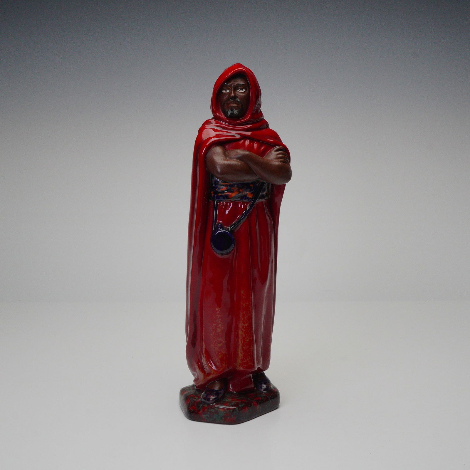Royal Doulton by Alan Maslankowski Flambe Figurine, The Moor BA74: Limited edition, small size Prestige bone china figure. It depicts a cloaked figure standing with crossed arms masterfully designed in the distinctive flambe glaze. Royal Doulton backstamp.