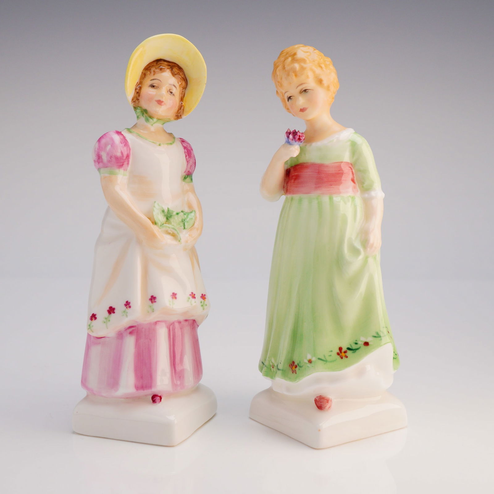 2pc Royal Doulton Figurines, Emma HN 2834 and Tess HN 2865: The lot consists of Emma, model HN 2834, and Tess, model HN 2865. Emma is depicted wearing a yellow sun hat, a pink and white dress, and holding foliage, marked with a 1979 copyright. Tess is shown in