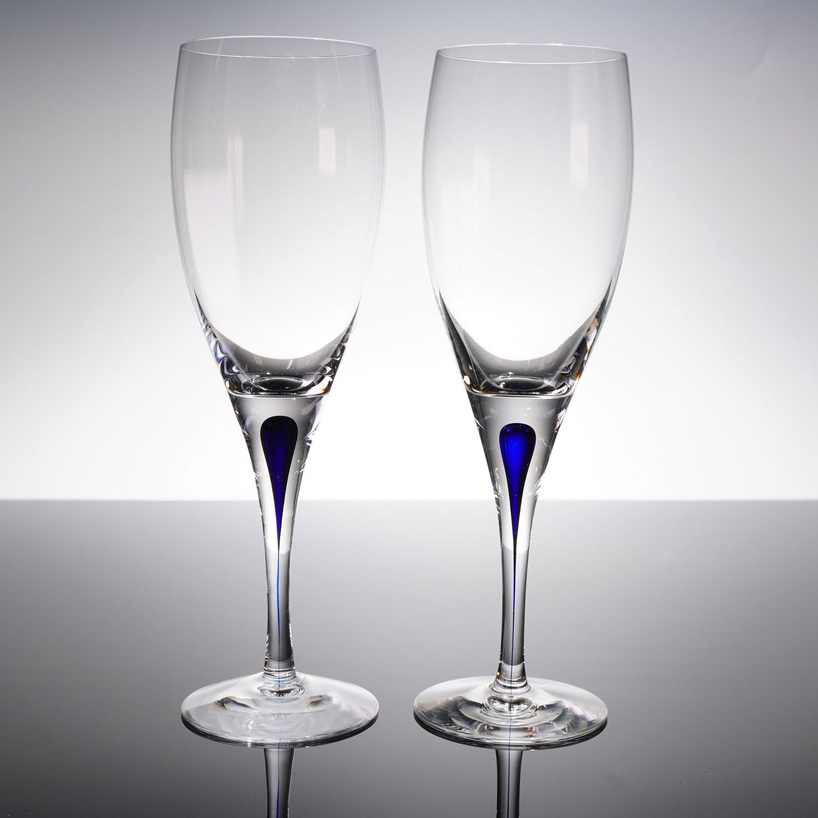 A Pair of Orrefors Intermezzo Crystal Champagne Flutes: A pair of contemporary crystal champagne fi?utes designed by Erika Lagerbielke for Orrefors, in the Intermezzo Blue patern. The glasses feature a tall, slender bowl suitable for sparkling wine, suppor