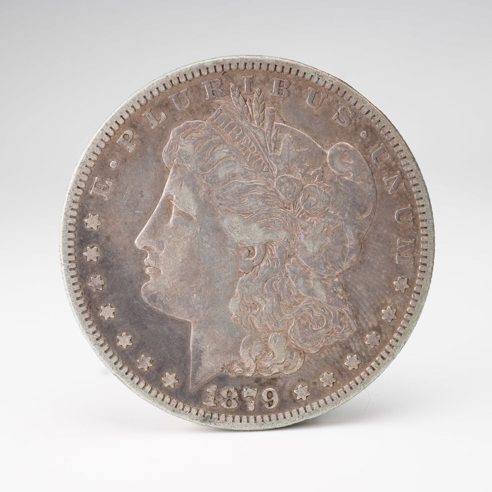 1879-S Morgan Silver Dollar: An 1879-S Morgan Silver Dollar, struck at the San Francisco Mint and designed by George T. Morgan. The obverse displays the classical profile of Liberty, crowned with a Phrygian cap encircled by