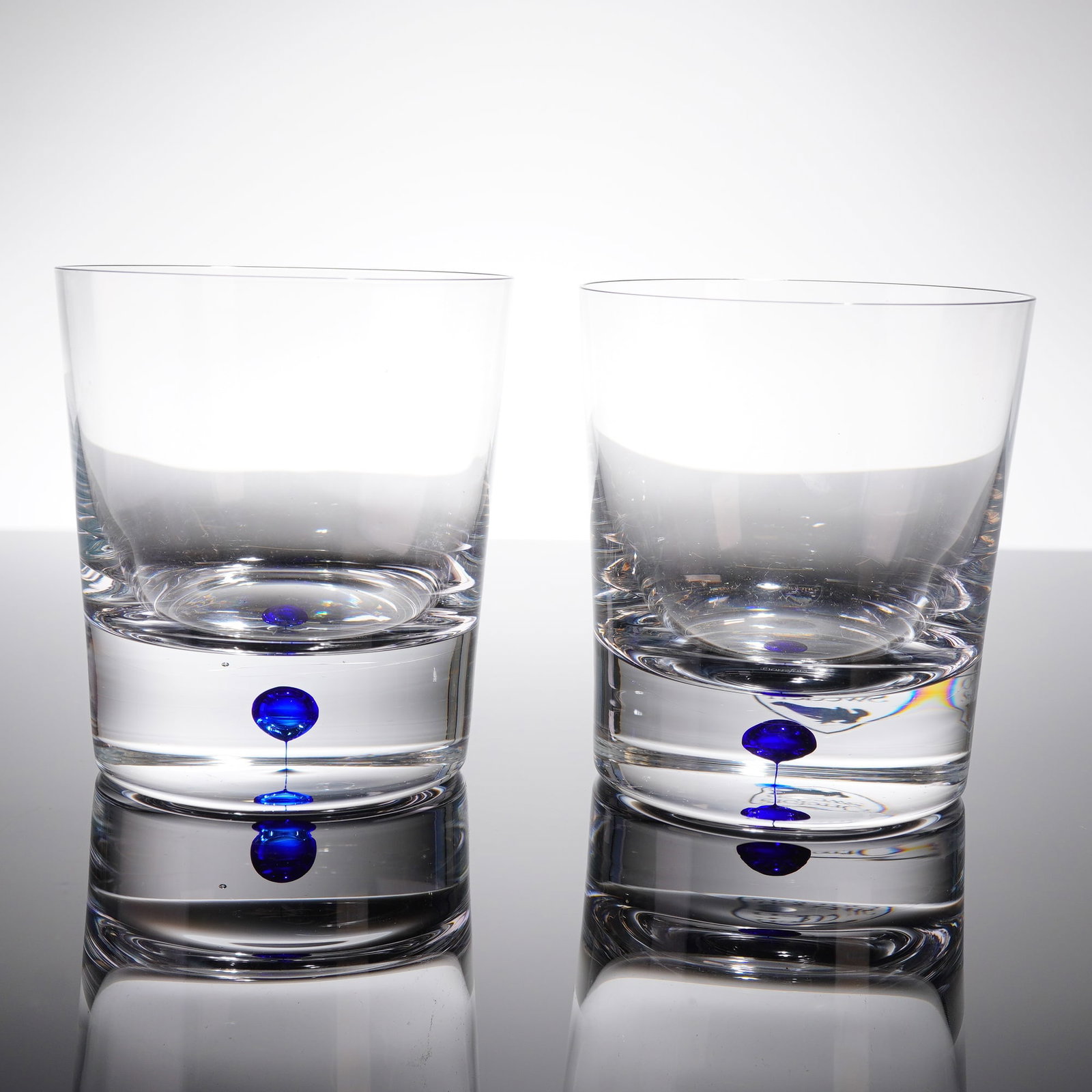 A Pair of Orrefors Intermezzo Double Old Fashioned Glasses: A pair of Orrefors Intermezzo Blue Double Old Fashioned glasses. These items are crafted from clear, crystal and are atributed to the Mid-Century Modern or late 20th-century period. The glasses