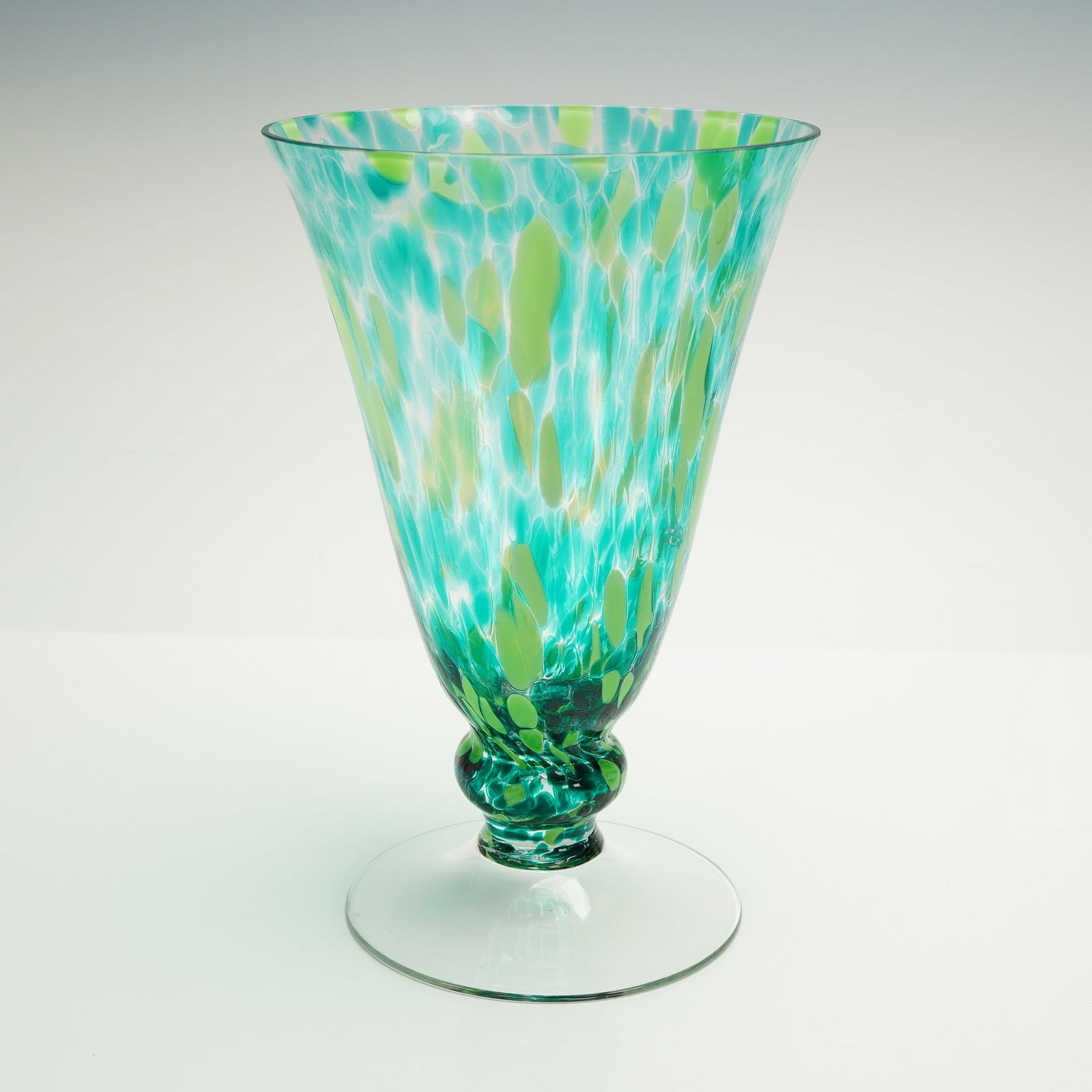 Artisan Speckled Art Glass Pedestal Vase: A single hand-blown glass vessel designed as a pedestal vase. The tall, flared body is decorated internally using a macchia or confetti technique, featuring irregular fragments of turquoise, teal, and
