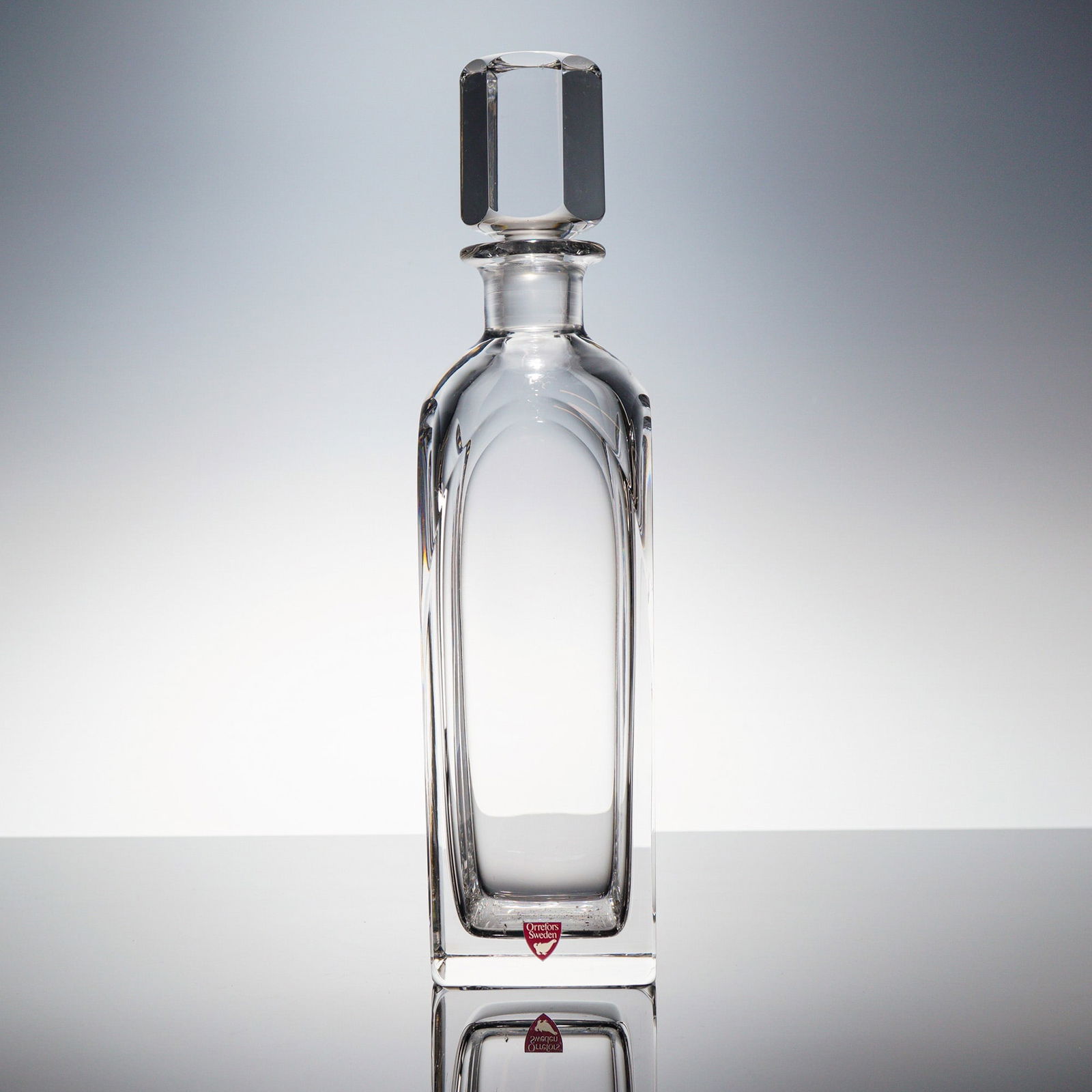 Edward Hald for Orrefors Crystal Decanter with Stopper: A clear, heavy crystal decanter set designed by Edward Hald for Orrefors, Sweden. The set consists of a square-bodied vessel and a geometric, faceted stopper. The vessel features sharp external geomet