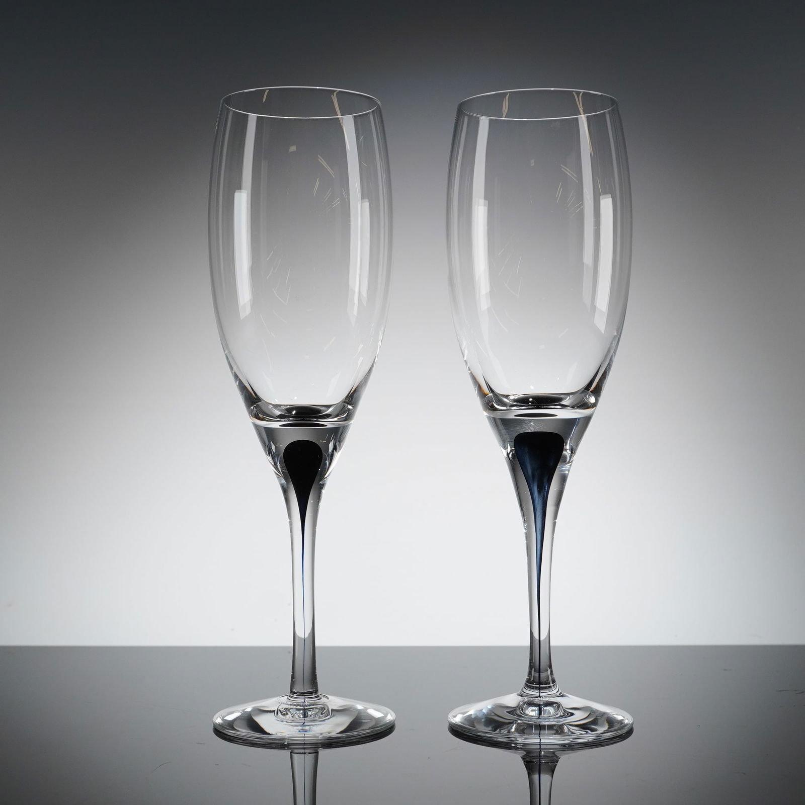 Pair of Orrefors Intermezzo Blue Champagne Flutes: A pair of modern crystal champagne flutes designed by Erika Lagerbielke for Orrefors in the Intermezzo patern. Each fi?ute features a tall, narrow bowl suitable for champagne, supported by a slender s