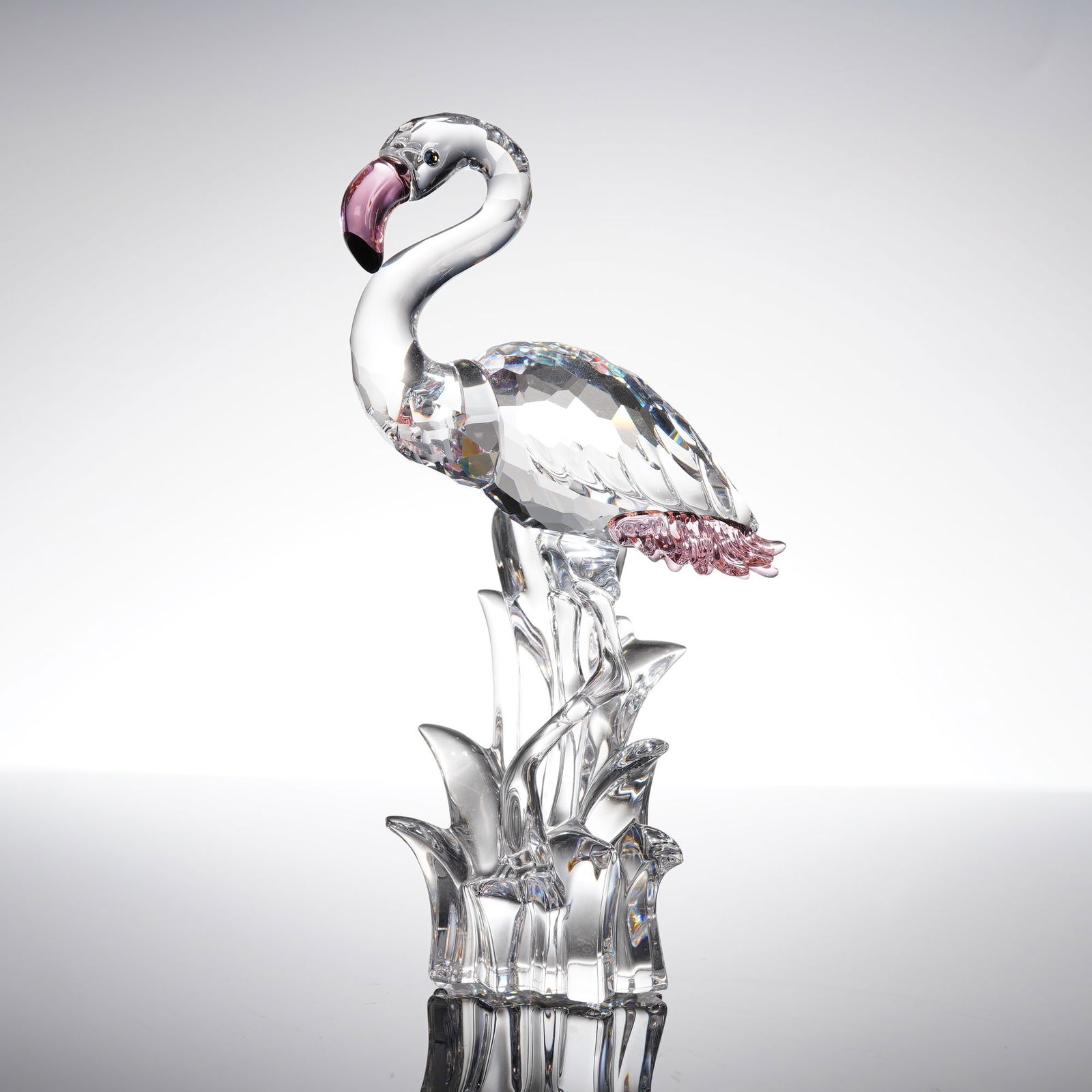 Swarovski Crystal Figurine Flamingo: A single crystal figurine manufactured by Swarovski, depicting a flamingo standing on stylized crystal reeds. The flamingo features colored accents applied to the tip of the beak and the tail feathers