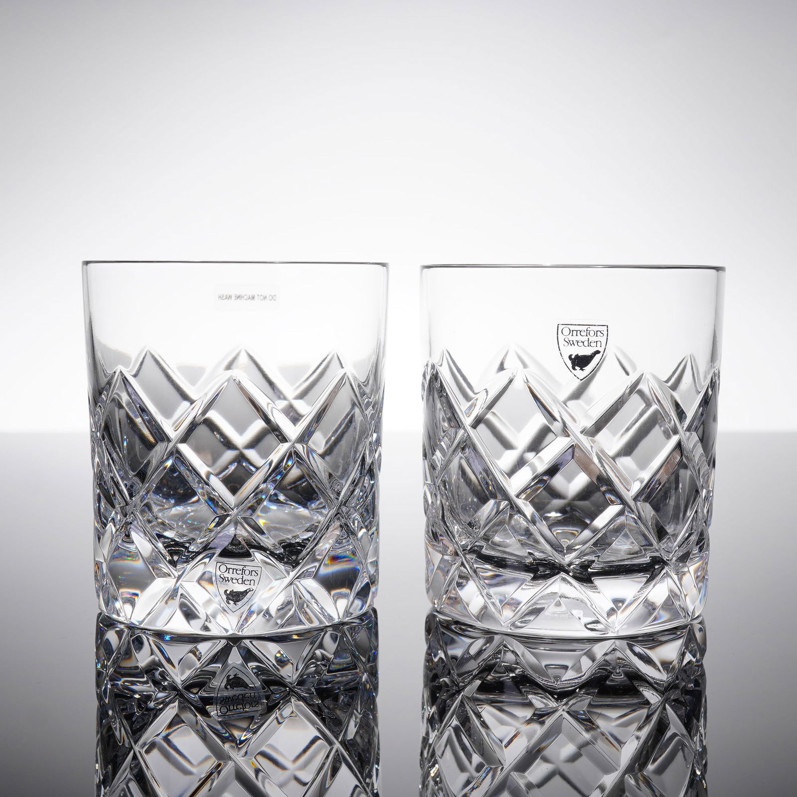 Pair of Orrefors Peak Double Old Fashioned Crystal Glasses: A collection of two Orrefors Peak Double Old-Fashioned Glasses. These heavy, clear crystal tumblers are characterized by a deep, geometric diamond-cut patern covering the exterior walls. The style is