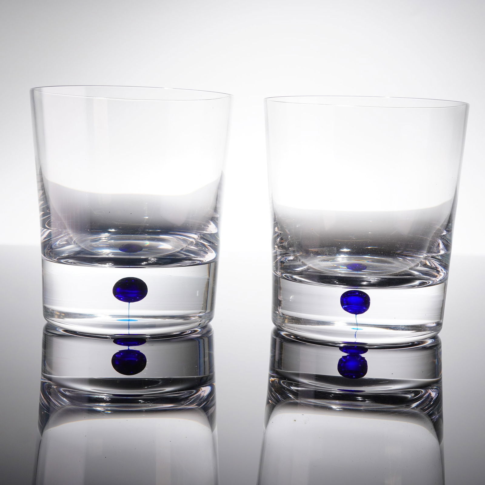 A Pair of Orrefors Intermezzo Crystal Double Old Fashioned Glasses: A pair of Orrefors Intermezzo Blue crystal Double Old Fashioned whiskey glasses. These modern heavy crystal tumblers feature a cylindrical form with a thick, solid base, consistent with Mid-Century