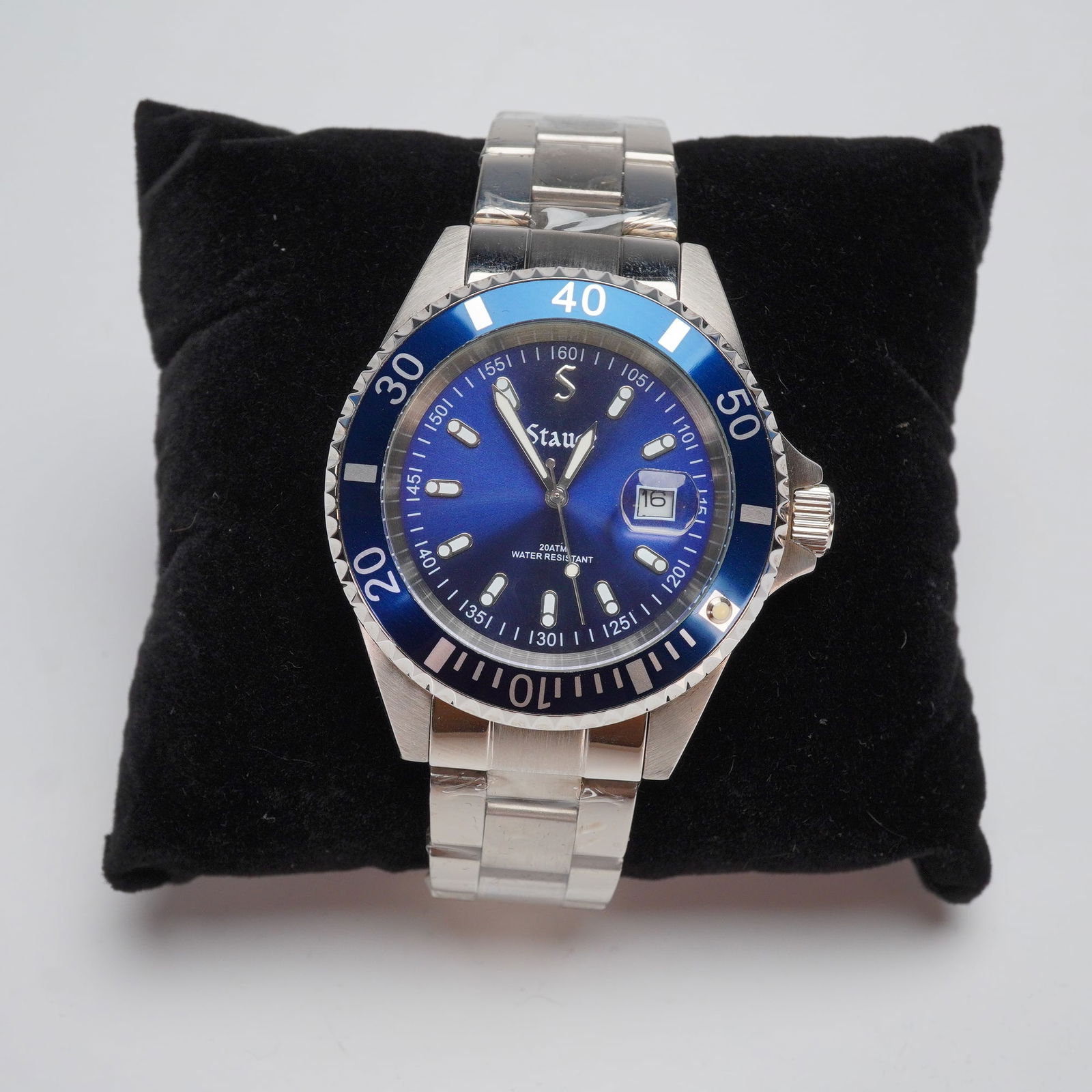 Stauer Excursion Dive Watch: This timepiece is a dive-style wristwatch constructed with a stainless steel case and a three-link stainless steel bracelet. It features a blue sunburst dial with luminous indices, a date window at