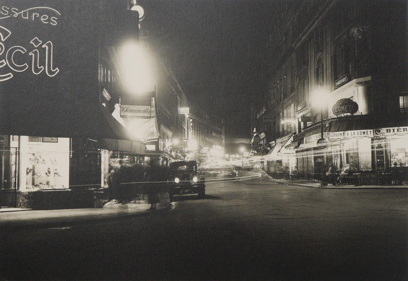 French Gelatin Silver Print Paris 1925 Faubourg Montmartre: A high-contrast gelatin silver print on board capturing a bustling Parisian night streetscape. The long exposure technique creates dramatic motion blur in the traffic, including an automobile and pede