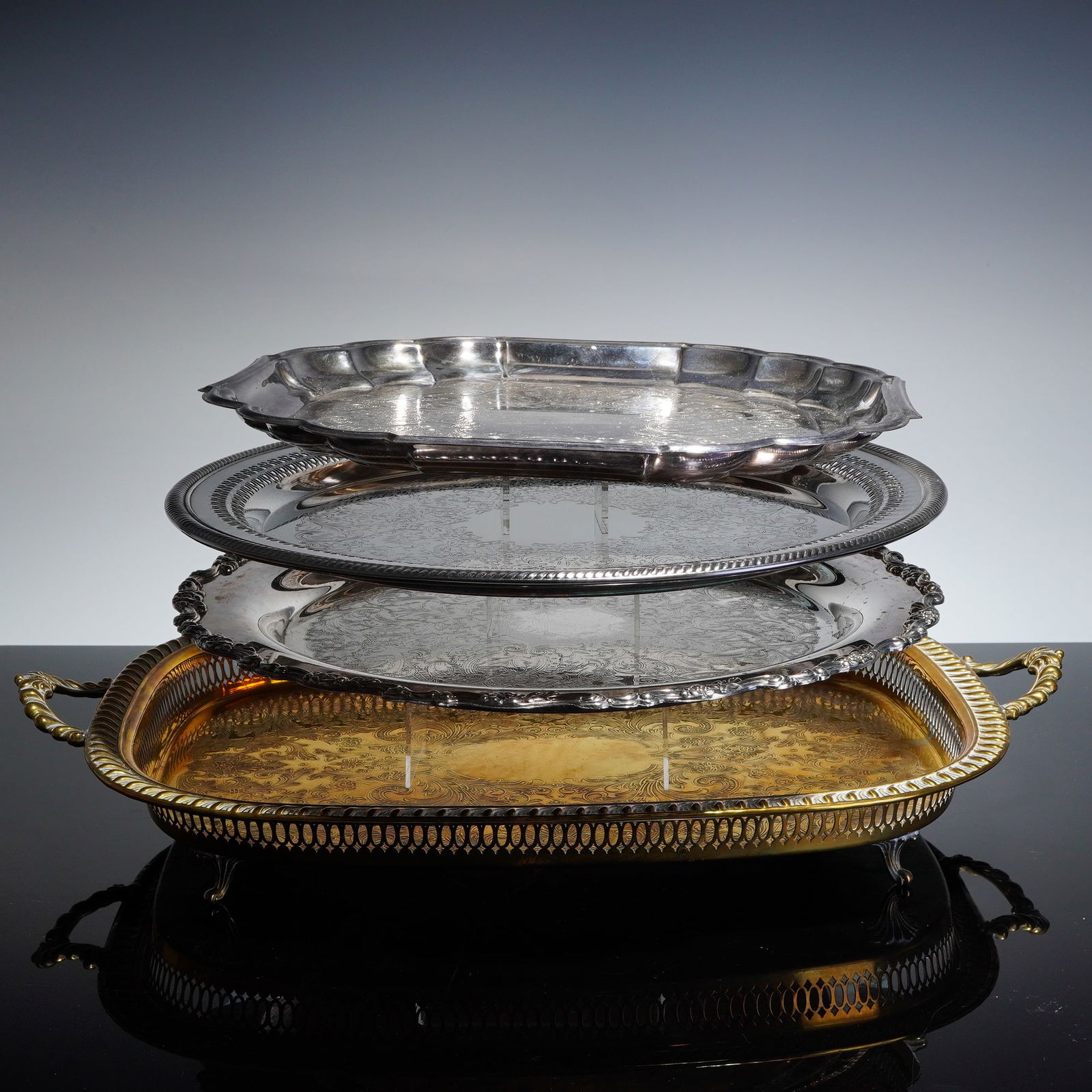 4pc Gorham, Oneida and Other Silver-Plated and Gilt Serving Trays: A collection of four decorative serving trays, primarily composed of electroplated nickel silver (EPNS) or silver plate, with one large footed tray featuring a contrasting gold-tone. The largest item