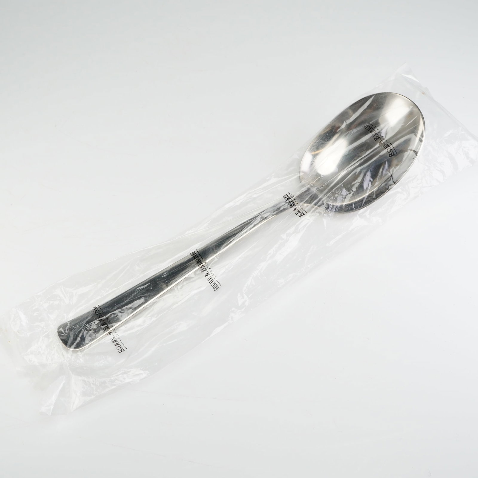Robbe & Berking Stainless Steel Serving Spoon: The item is constructed from polished 18/8 stainless steel (Edelstahl), displaying a simple, utilitarian design typical of modern flatware. The shanks of the spoons are stamped with the maker's mark R