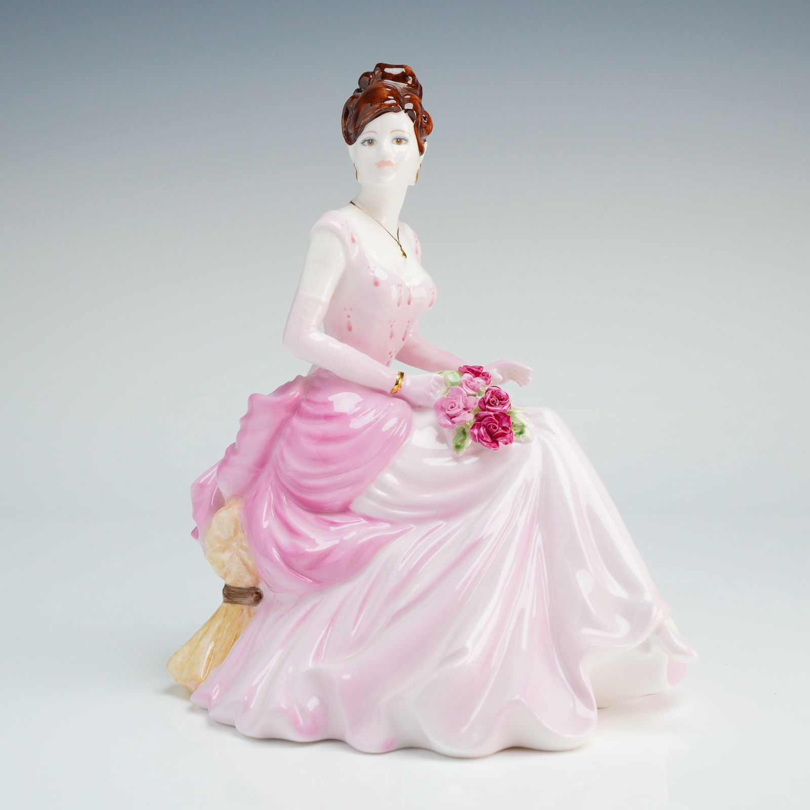 A Coalport Bone China Figurine, Happy Birthday: Coalport bone china figurine titled Happy Birthday, modeled by Jack Glynn as part of The Willis Collection, Collector's Choice - 2001. The hand-decorated piece depicts a seated lady with auburn hair s