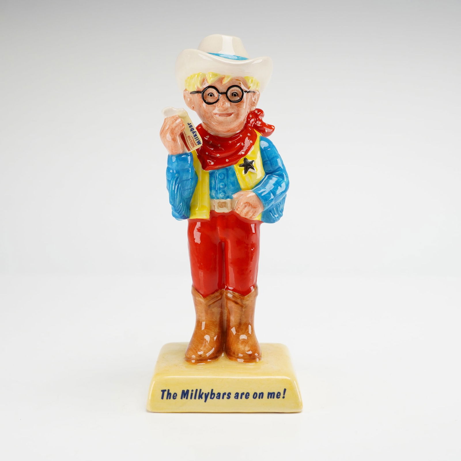 Royal Doulton Advertising Character, The Milky Bar Kid AC7: A Royal Doulton from the 20th Century Advertising Classics series. This Royal Doulton advertising character depicts the blond-haired mascot in cowboy attire, featuring a white hat, blue shirt, yellow